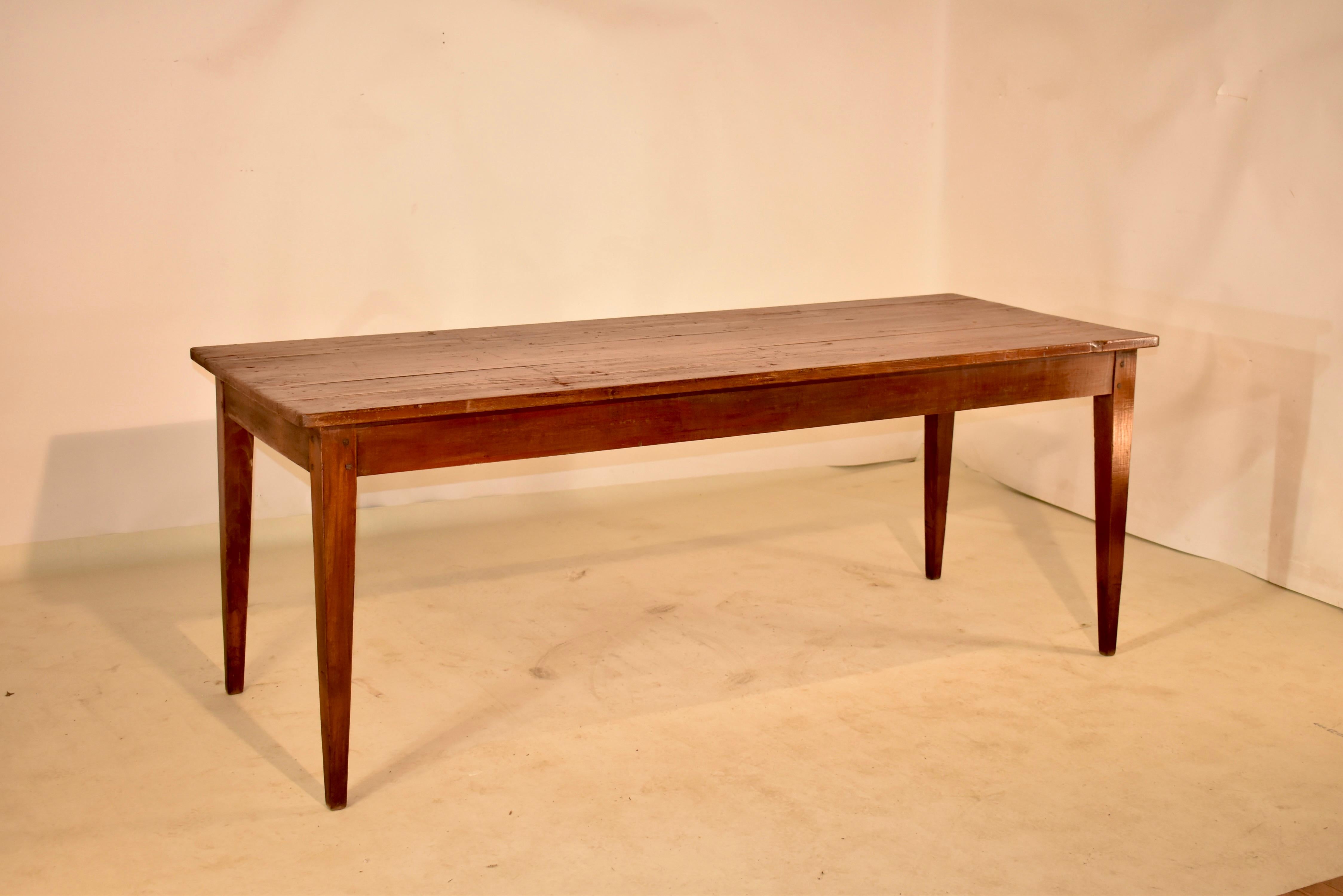 Early 19th century farm table from France made from pine and elm. The top is made from pine planks, and is supported on an elm base, which has a simple apron that measures 25 inches in height and follows down to simply elegant tapered legs. The