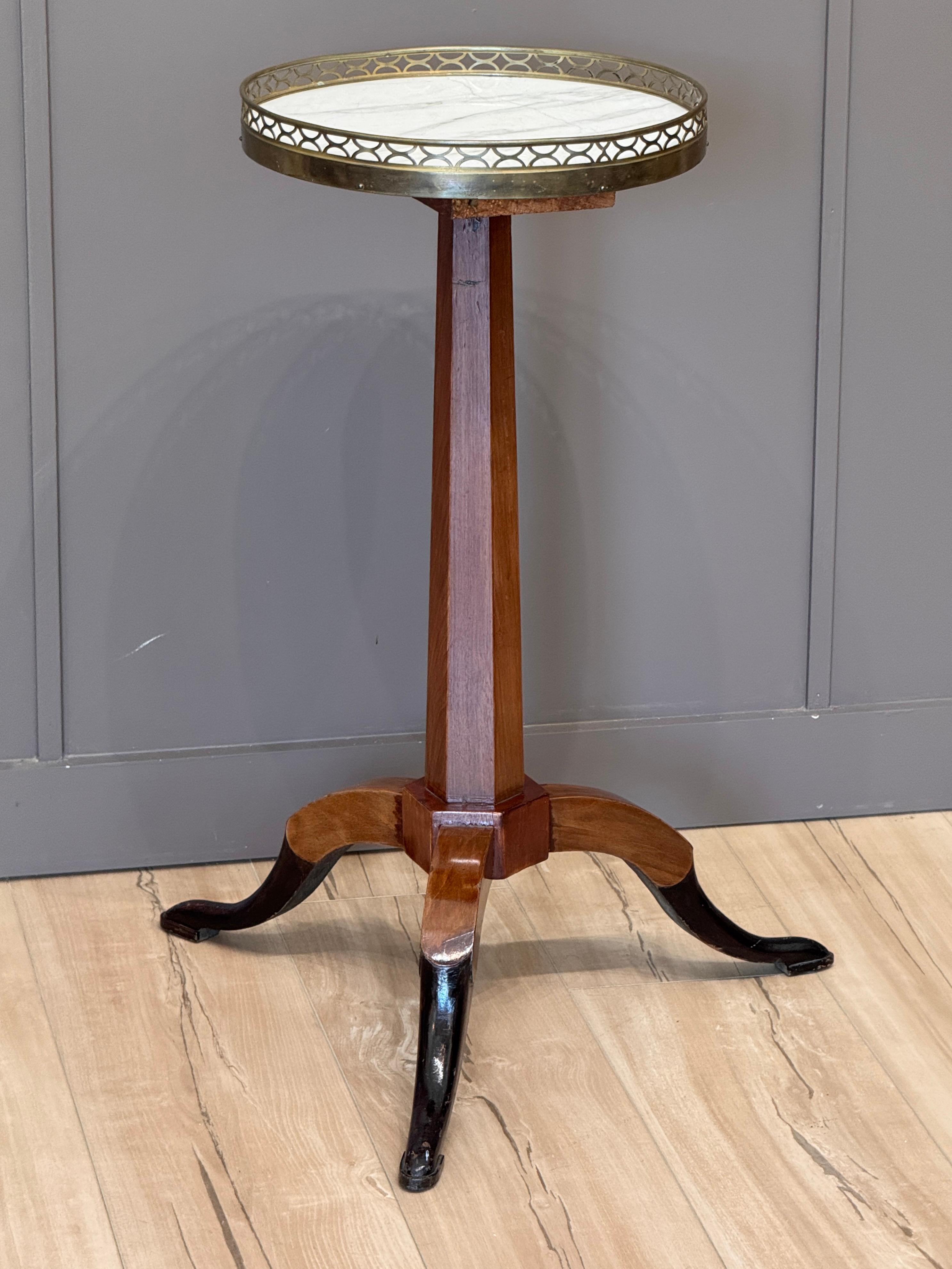 Chandelier néoclassique français du début du XIXe siècle en marbre et bois fruitier, avec galerie en bronze doré percée, reposant sur des pieds en coussinets ébonisés évasés. 