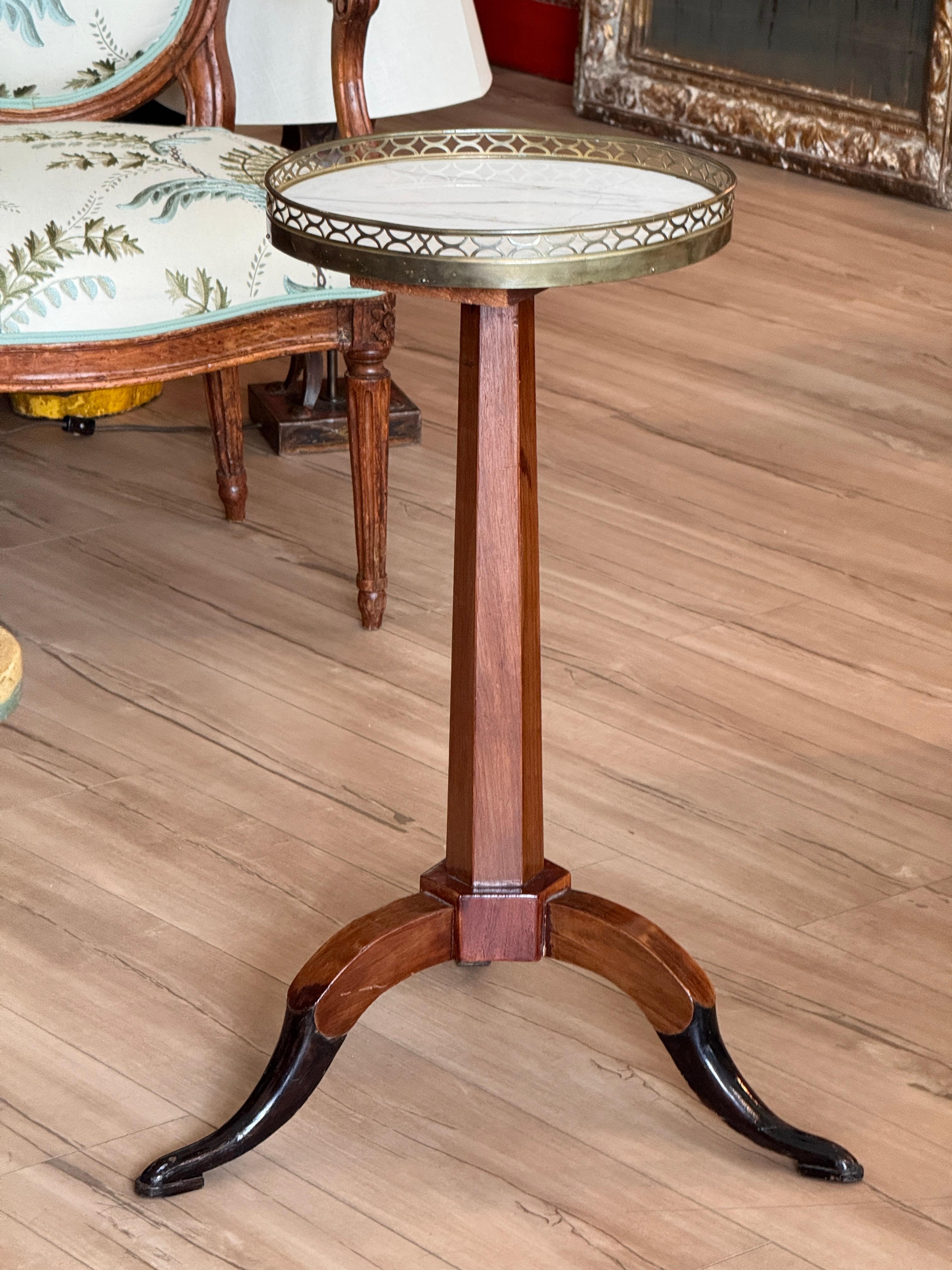 Table chandelier française du début du 19e siècle en bois fruitier, avec un plateau circulaire en marbre blanc subtilement veiné et un entourage de galerie en laiton percé. La tige effilée repose sur trois pieds gracieusement incurvés. L'image de