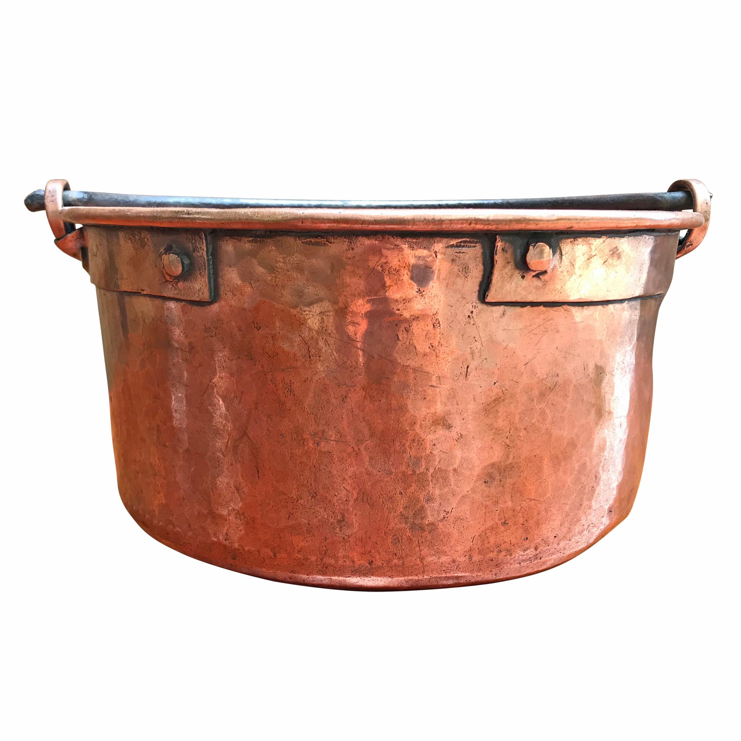 An early 19th century French hammered copper kettle with wide riveted copper straps, a thick hand-forged iron handle, and scalloped dovetail joinery around the bottom.