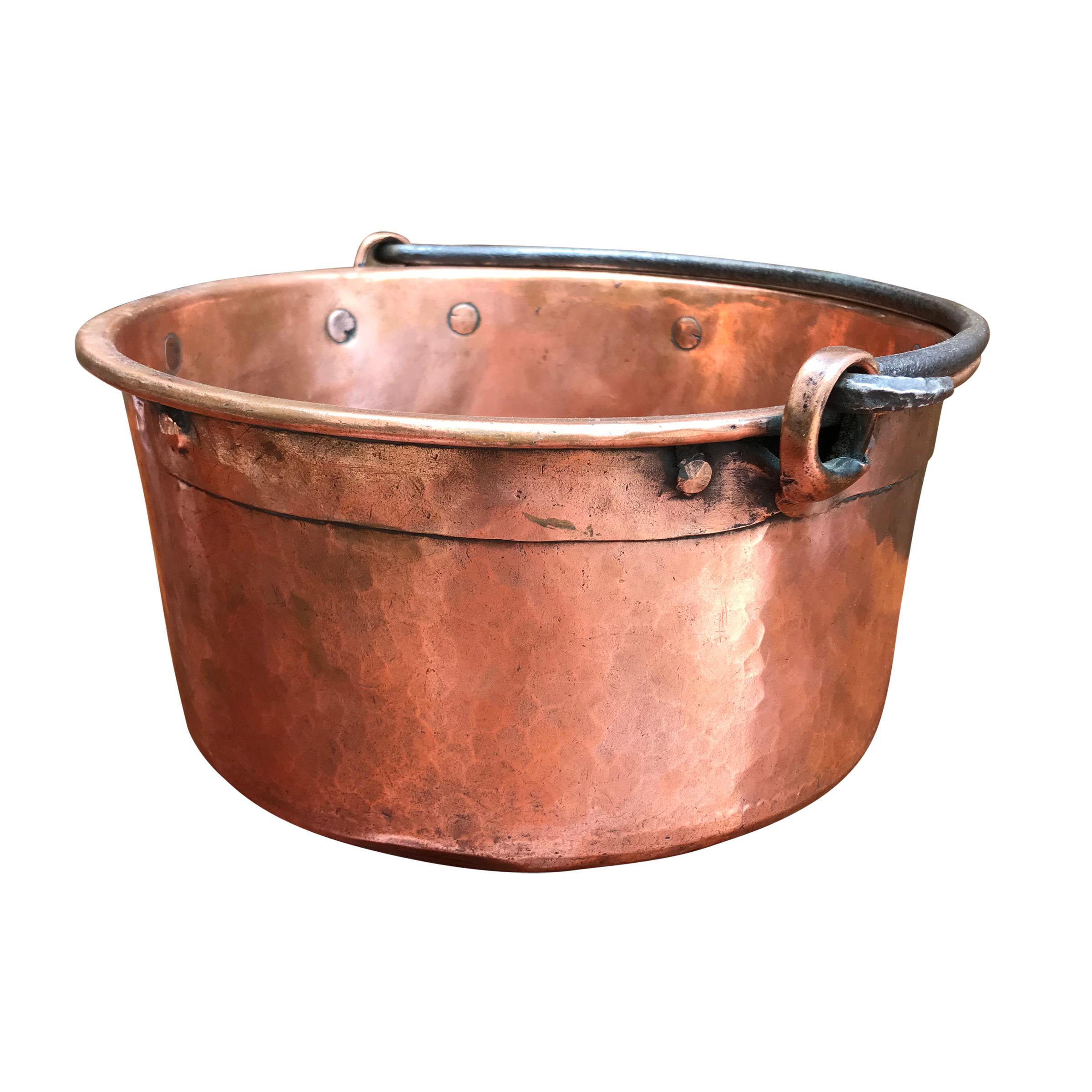 An early 19th century French hammered copper kettle with wide riveted copper straps, a thick hand-forged iron handle, and scalloped dovetail joinery around the bottom.