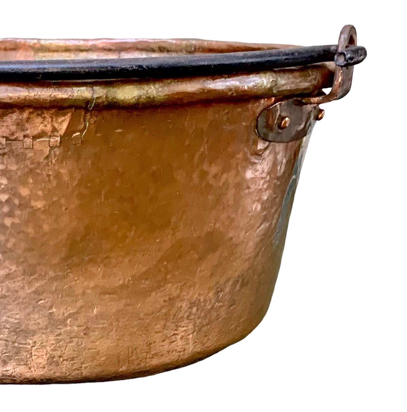 A large early 19th century, French Provincial hammered copper cooking pot/cauldron with a riveted iron swing handle and hand rolled rim with an extraordinary old finish/patina.
Although I have not detected any markings, this piece was beautifully