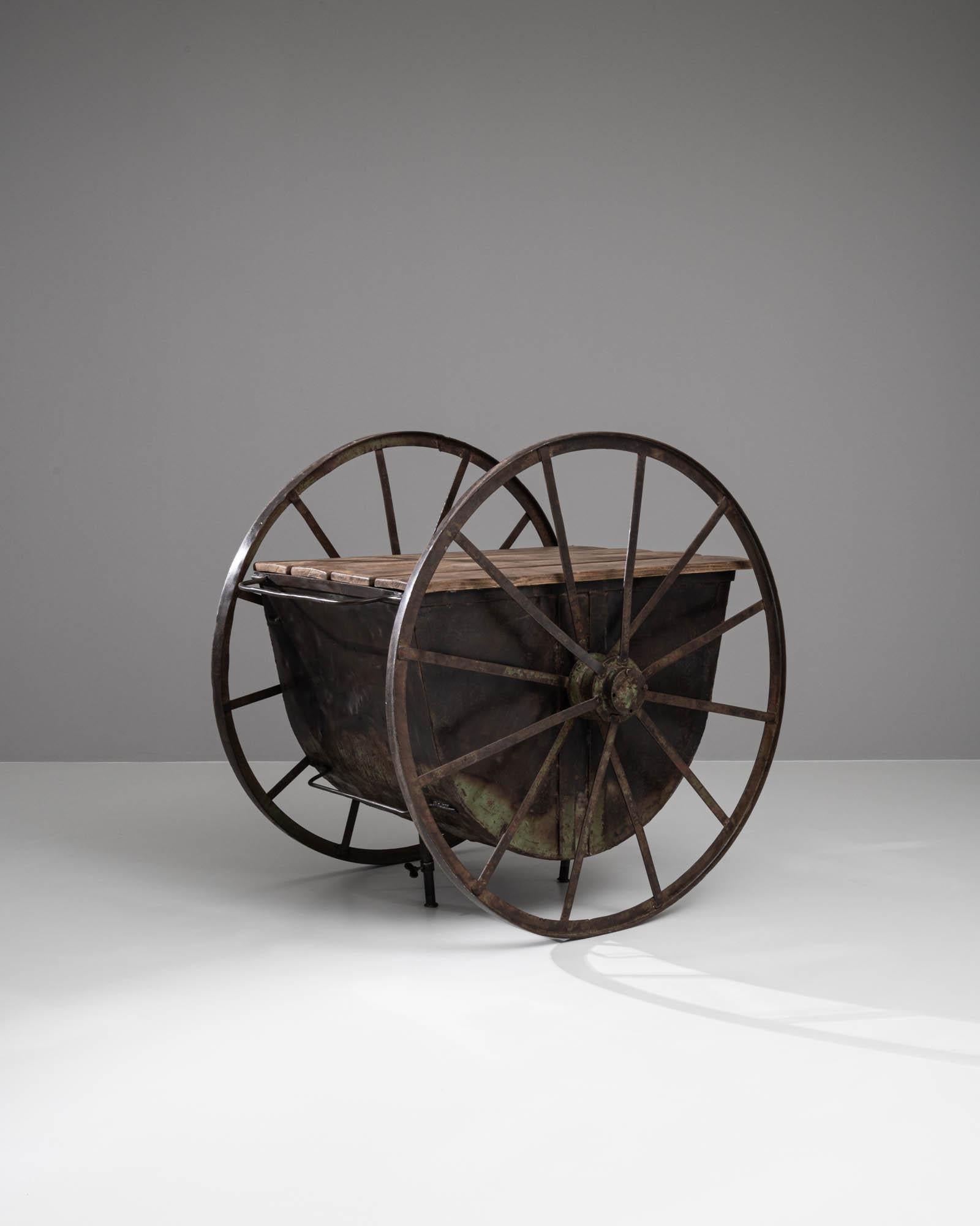 Cette table de travail industrielle française à roulettes du début du XIXe siècle est un objet remarquable qui capture magnifiquement l'essence de l'ère industrielle. Construite avec du métal robuste et des planches de bois robustes, cette table se