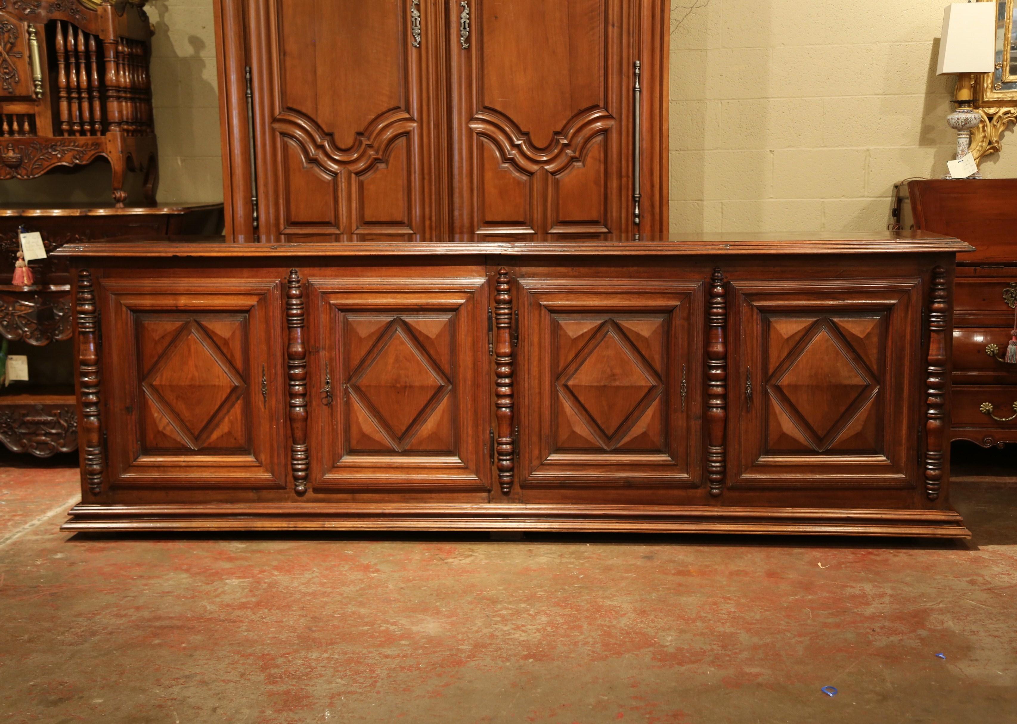 Place this long, antique fruitwood buffet in your dining room to function as a convenient serving and storage piece. Carved in the south of France, circa 1820, this large, impressive enfilade features four carved doors with simple, geometric diamond