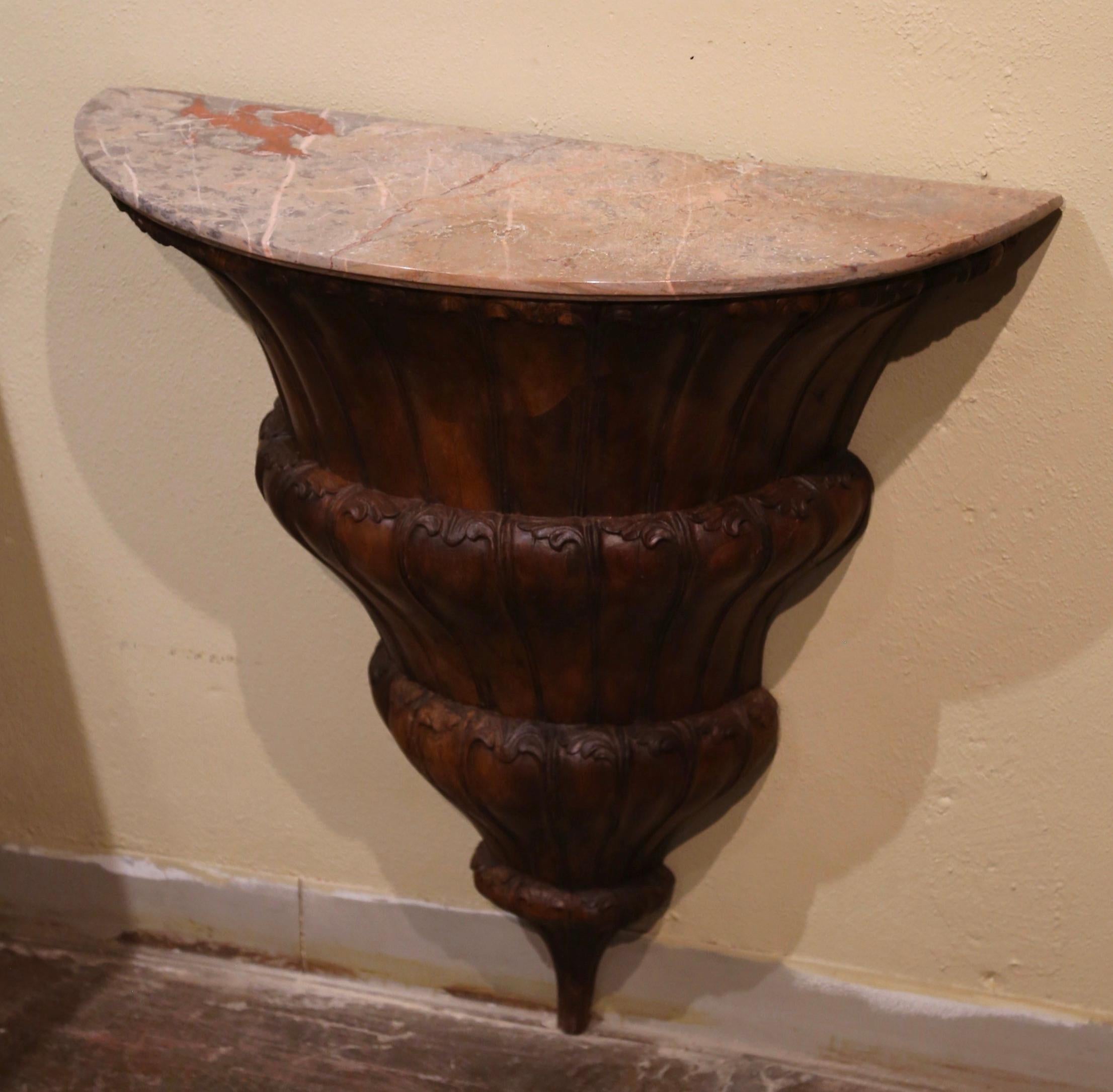 Decorate an entry or hallway with this elegant antique console. Crafted in southern France circa 1820 and built of walnut, the tapered and V-shaped table rests on the ground; it features hand carved wave motifs over a gadrooned body. The surface is