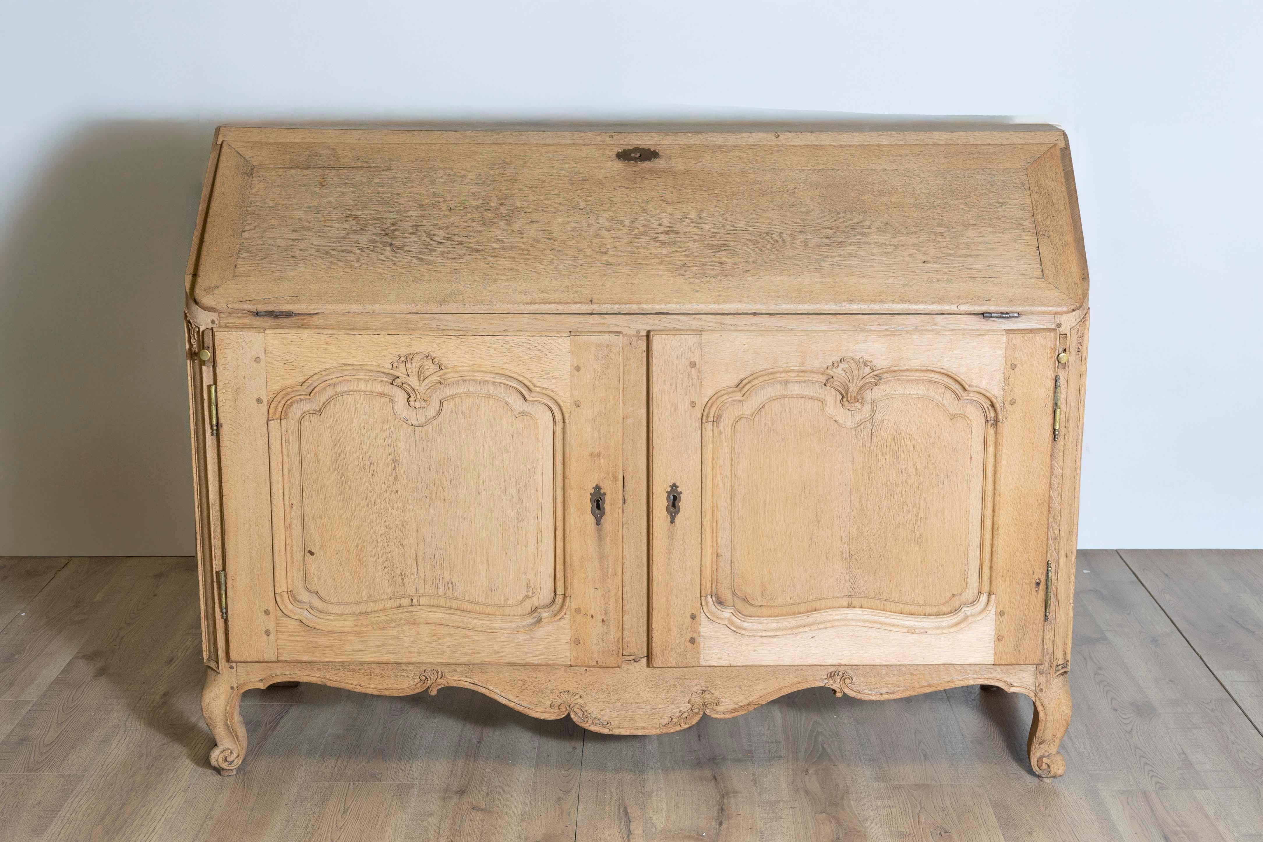 This Early 19th Century French Louis XV Style Secrétaire showcases a timeless and classy blend of functionality and elegance. Crafted from bleached oak, this piece features graceful curves and intricate detailing characteristic of the Louis XV