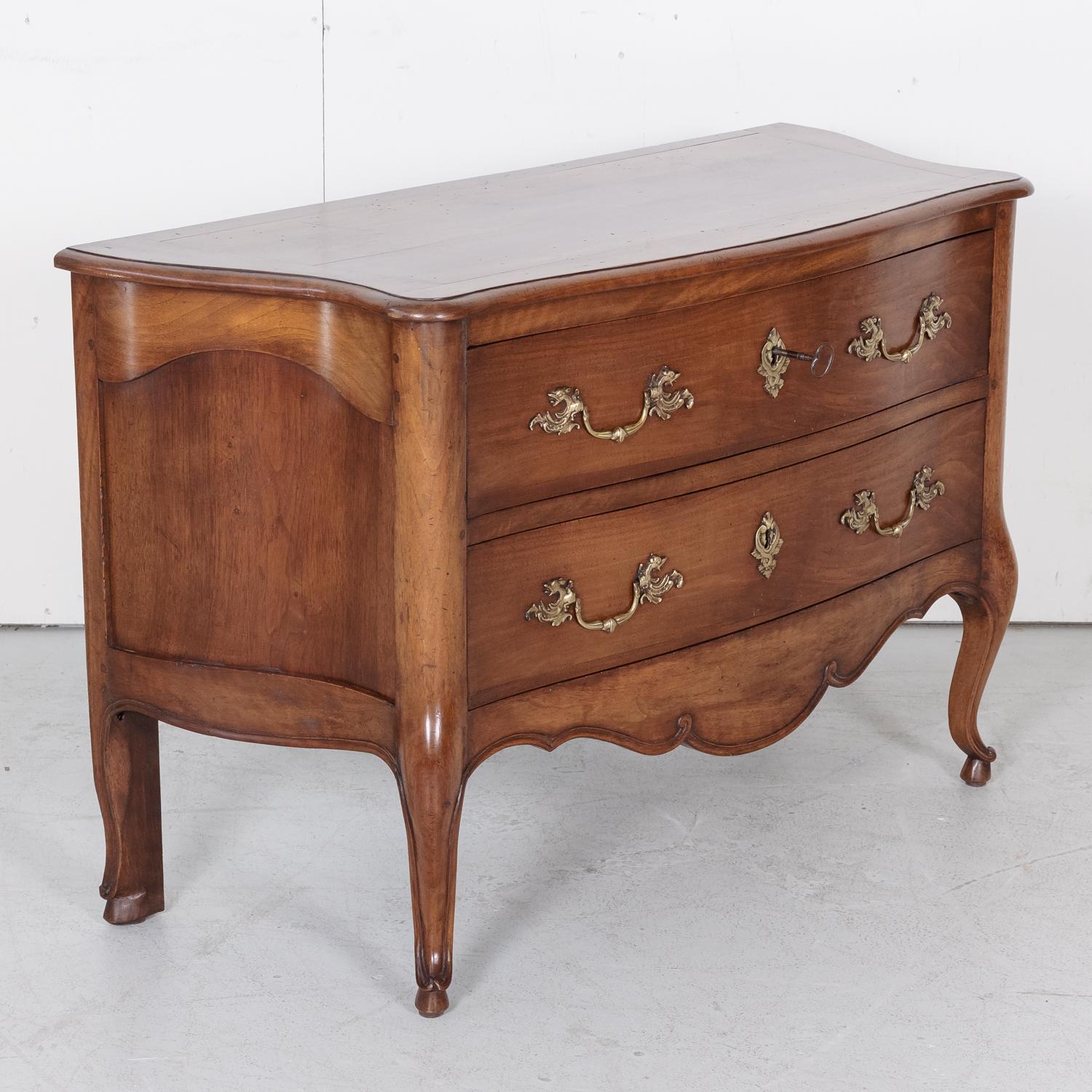 A fine 19th century French Louis XV style commode sauteuse handcrafted of solid walnut in Lyon, circa 1810. This elegant chest of drawers, also referred to as a 