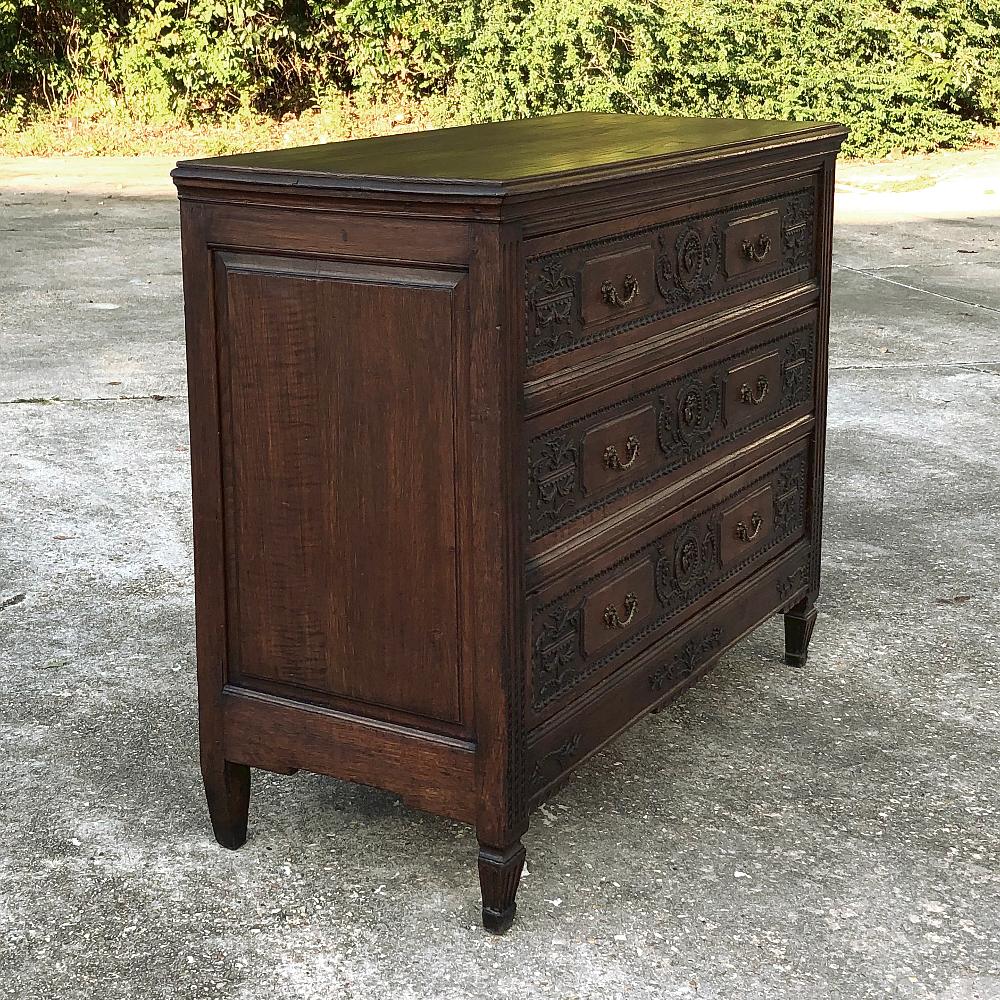 Early 19th century French Louis XVI commode represents the essence of talented rural artisans who copied the styles of the courts of Paris. Delicate bas relief carvings across the drawer facades are punctuated by cast bronze garland pulls, with