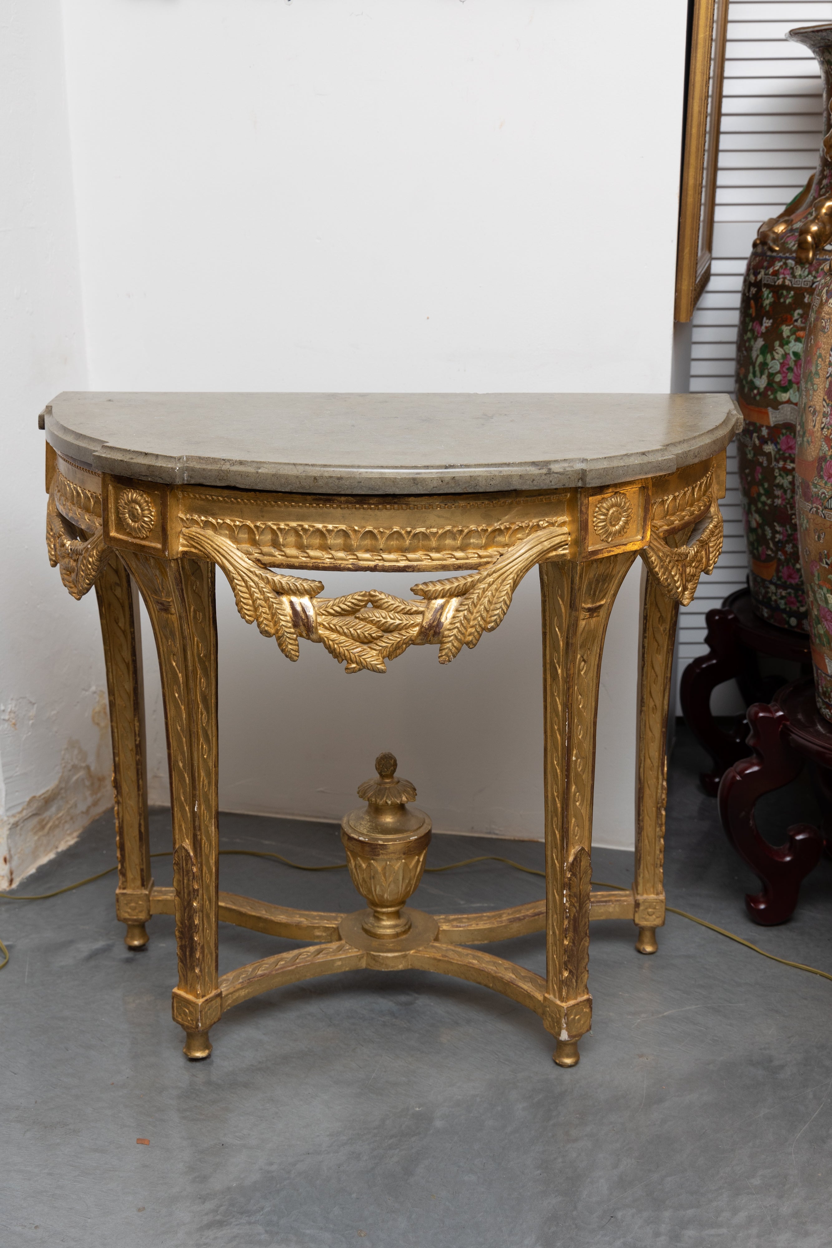 This is a lovely 19th century French Louis XVI demilune gilt console. The gray marble top is over an ornamental frieze with swags representing beards of wheat, supported by square legs and a curved stretcher centered by a prominent urn.