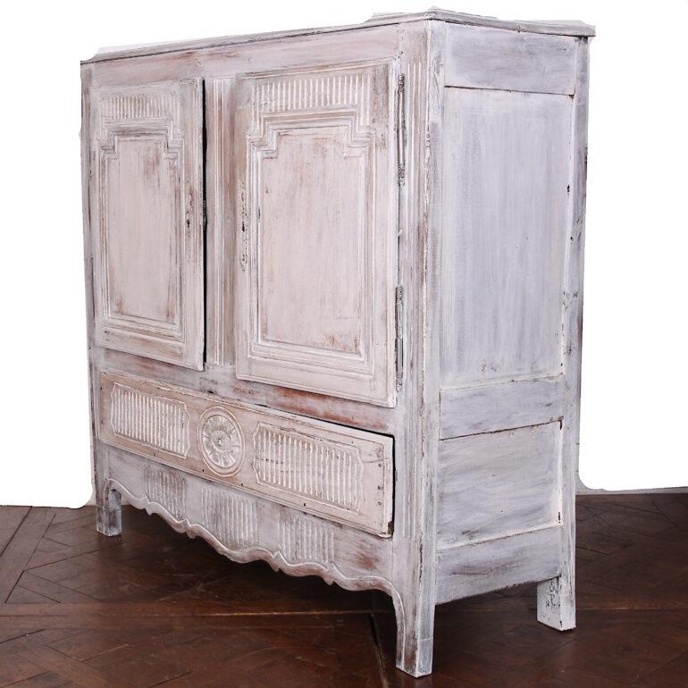 An early-19th century rustic carved French two-door cabinet with a later painted and distressed / waxed finish. Large drawer to base with carved medallion detail. 

  