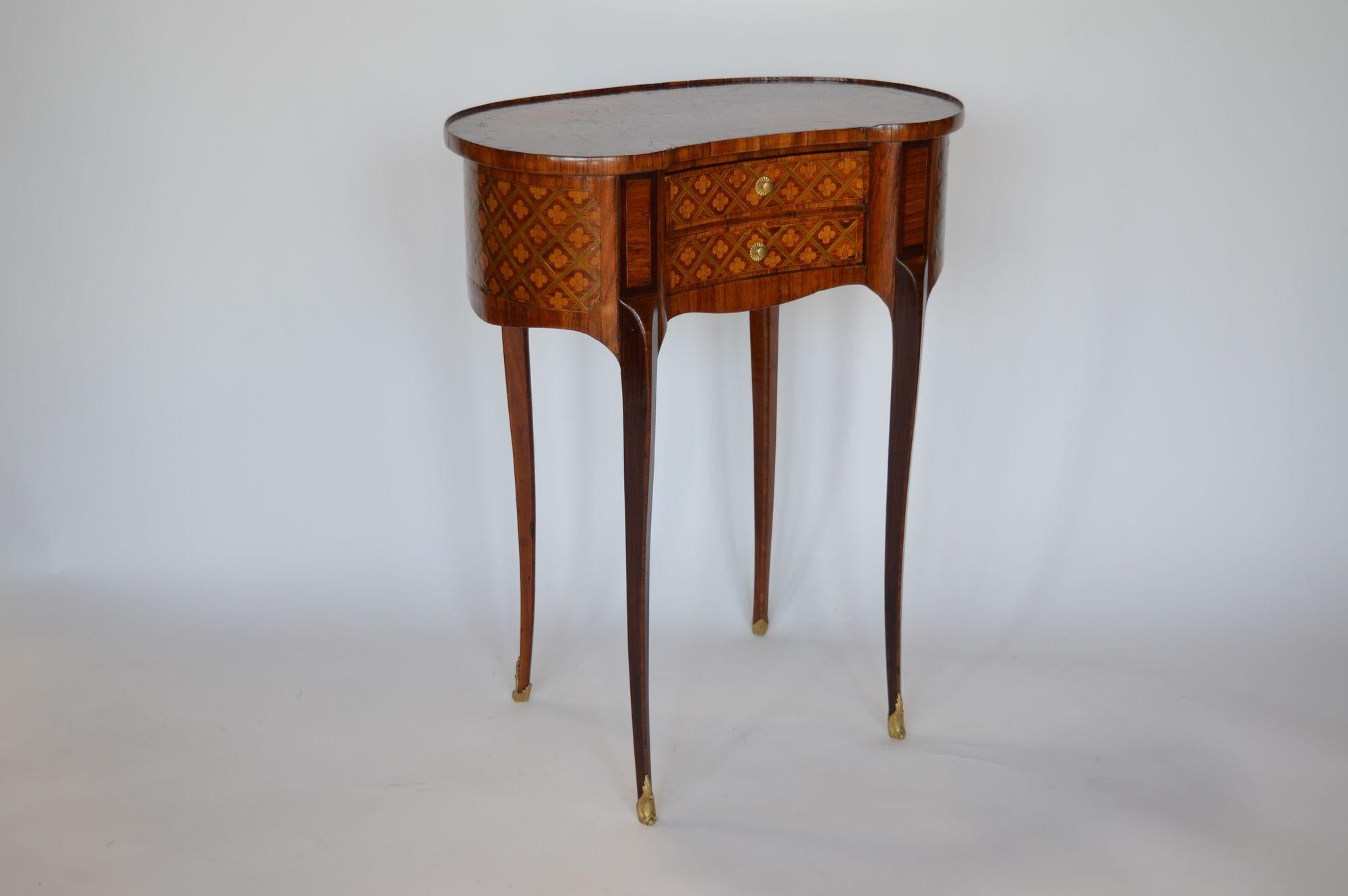 French marquetry occasional kidney-shape table with two drawers made in the early 19th century. Made with mahogany, maple and satinwood. The top of the table is carefully inlaid with flowered details. Consists of a beautiful parquetry design around