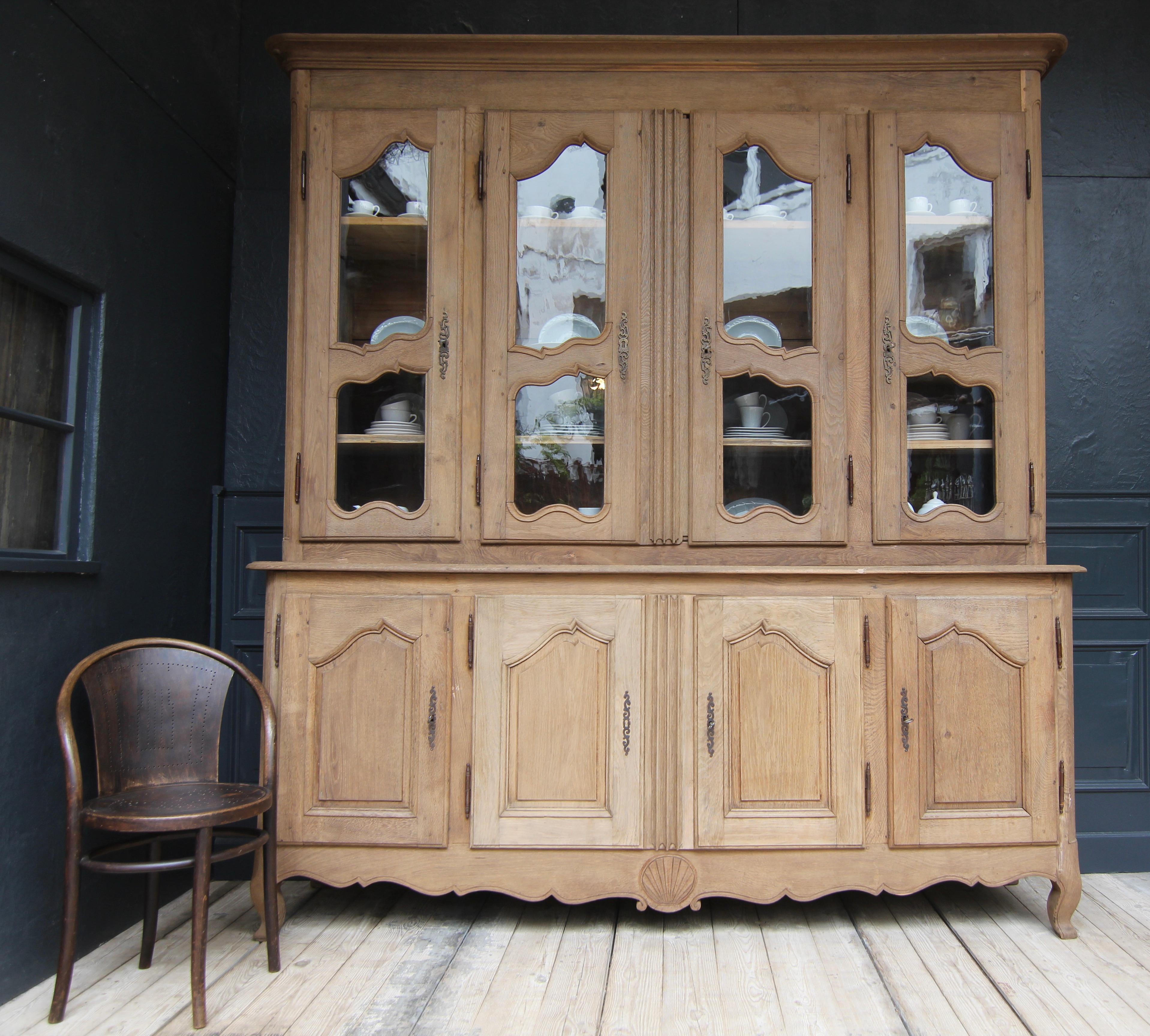 Large French provincial buffet à deux corps from the early 19th century. 

Two-part oak corpus standing on 4 feet and coffered at the sides with rounded pilasters and a total of 8 doors in frame construction hung on iron fittings on the outside.