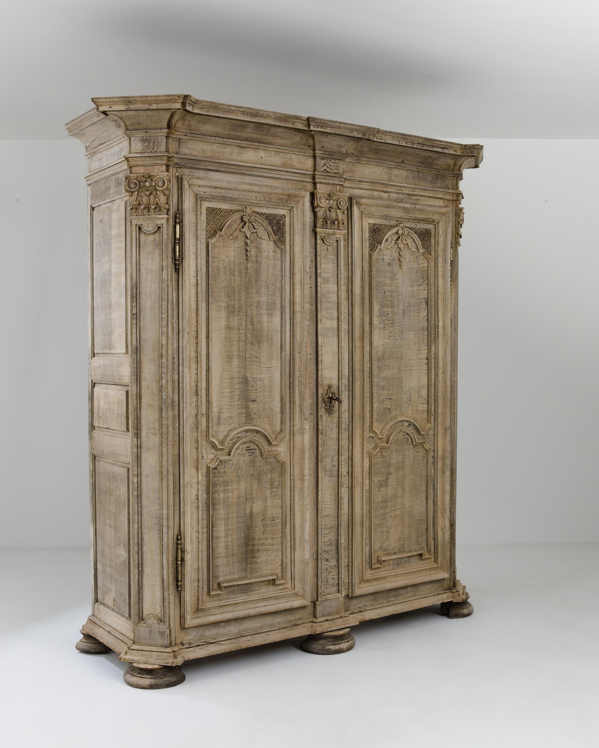 A wooden wardrobe created in France circa 1800. Towering above, this exquisite cabinet commands an impressive aura. Elaborately carved details dot key areas of the cabinet’s constructions, offering lovely moments of care and levity within its grand