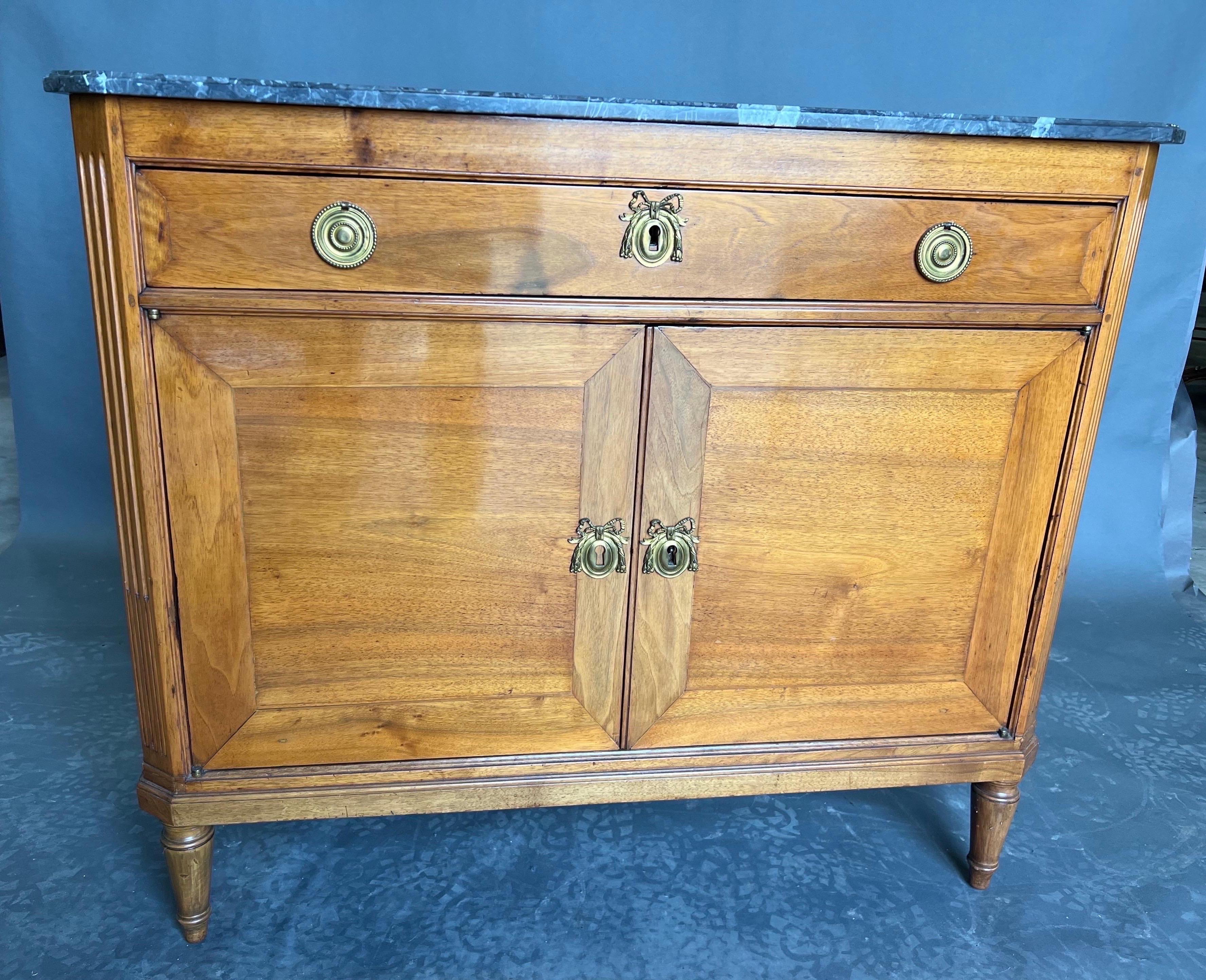 Beautiful early 19th century French or Baltic neoclassical walnut and marble top 2 door cabinet with canted corners and turned legs. This cabinet came from an incredible apartment in the Carlyle in Manhattan where the interior designer gave it a