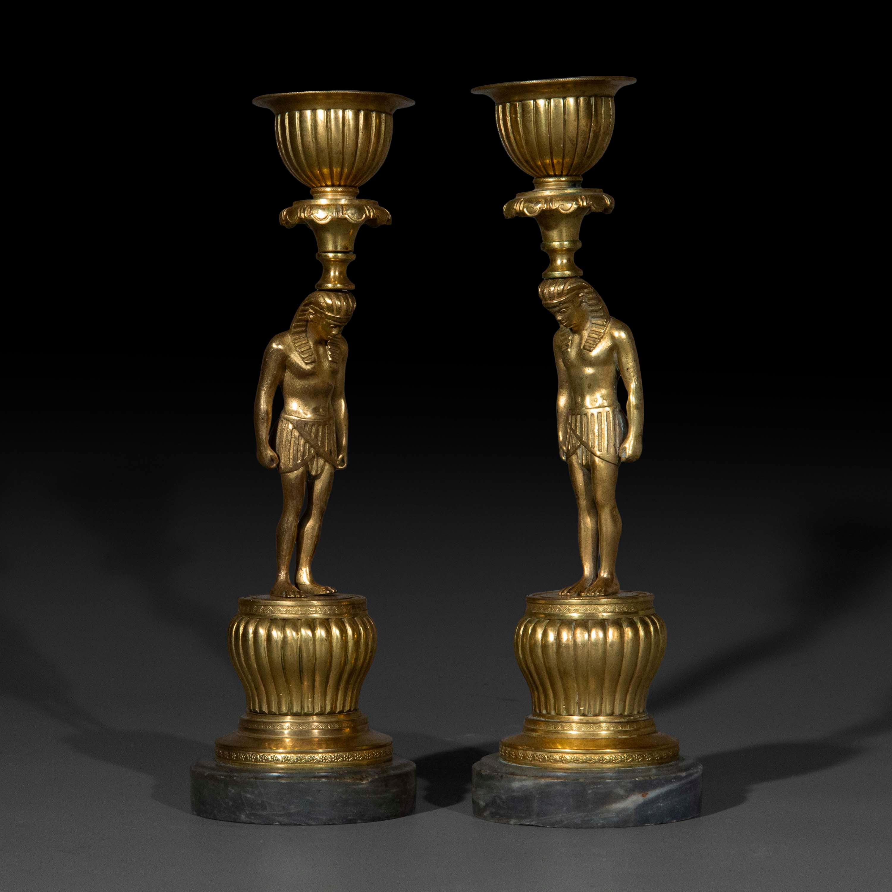 Candelieri francesi del XIX secolo in ormolu con figure di Antinoo in stile revival egiziano su basi in marmo blu Turchino. Circa 1810. Un modello raro e desiderabile.

Perché ci piacciono

Questa squisita coppia di candelabri francesi in ormolu del