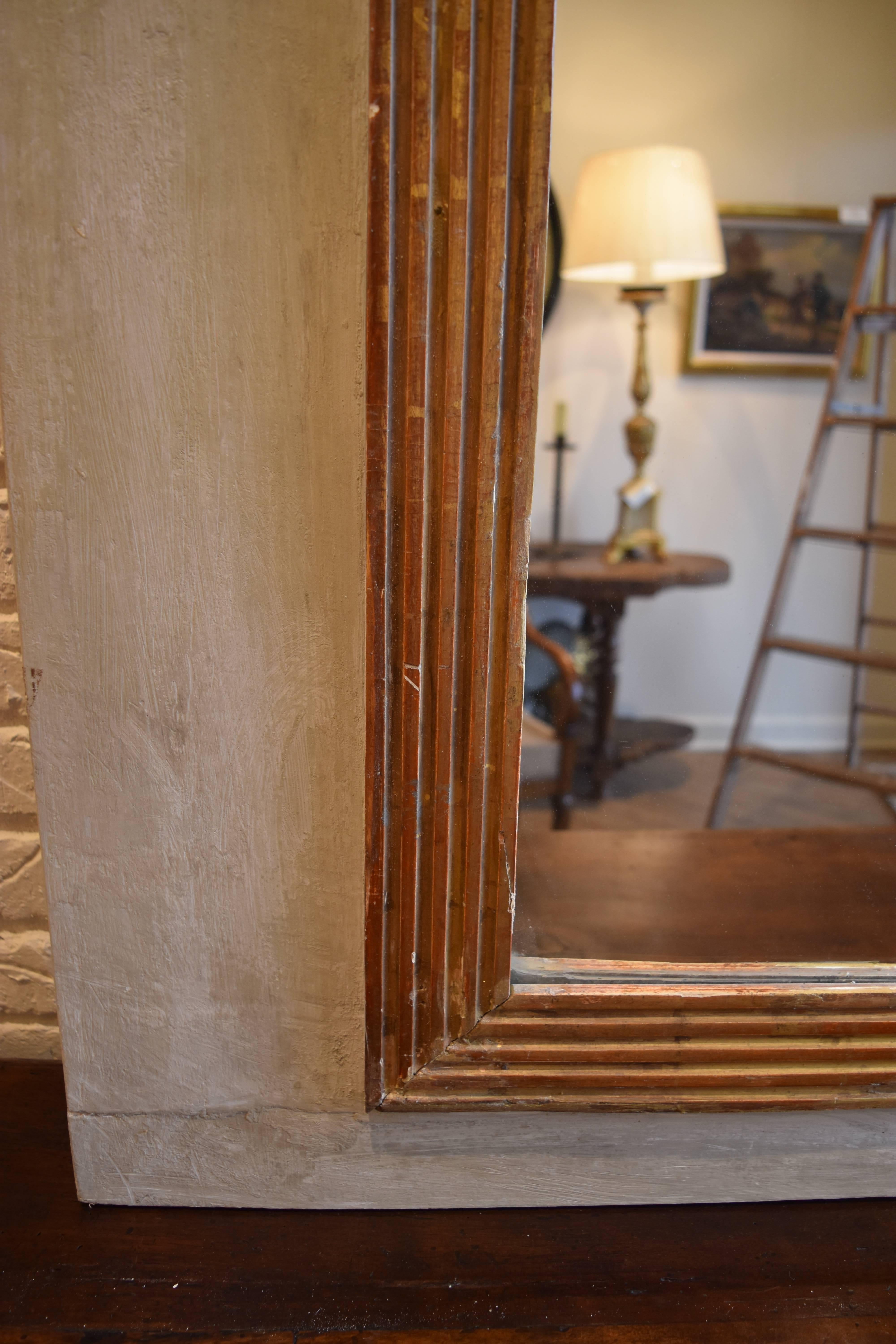 This tall mirror from the South of France has a lovely pale green / grey painted finish with reeded giltwood surrounding the plate glass. The glass appears to be old and the mirror back has the original hand planked wood as seen in the photos.