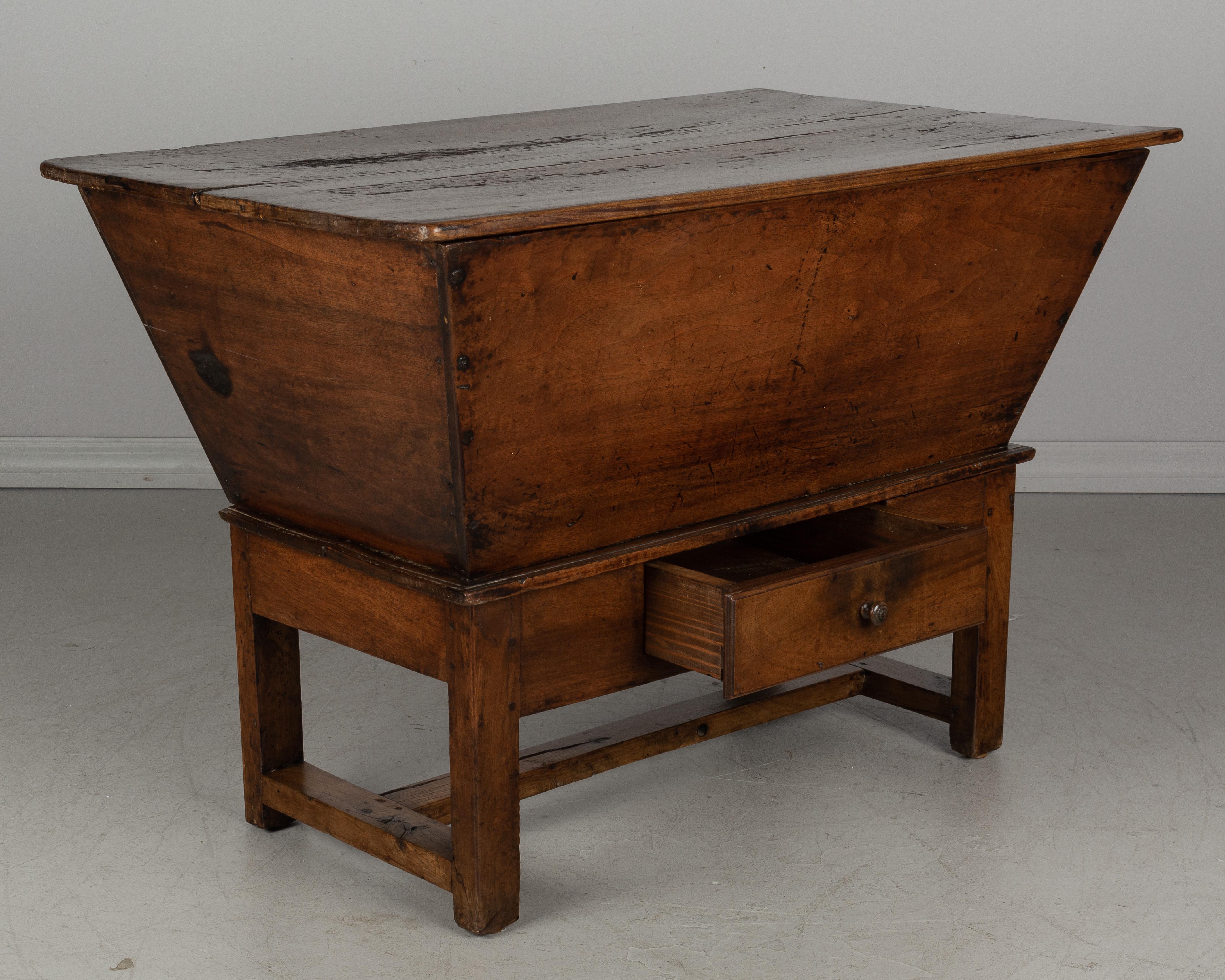 A large French pétrin, or dough bin, from the early 19th century made of thick planks of solid walnut. Also known as a kneading trough, this large box with slanted sides was used in bread making and has a removable lid to provide warmth for the