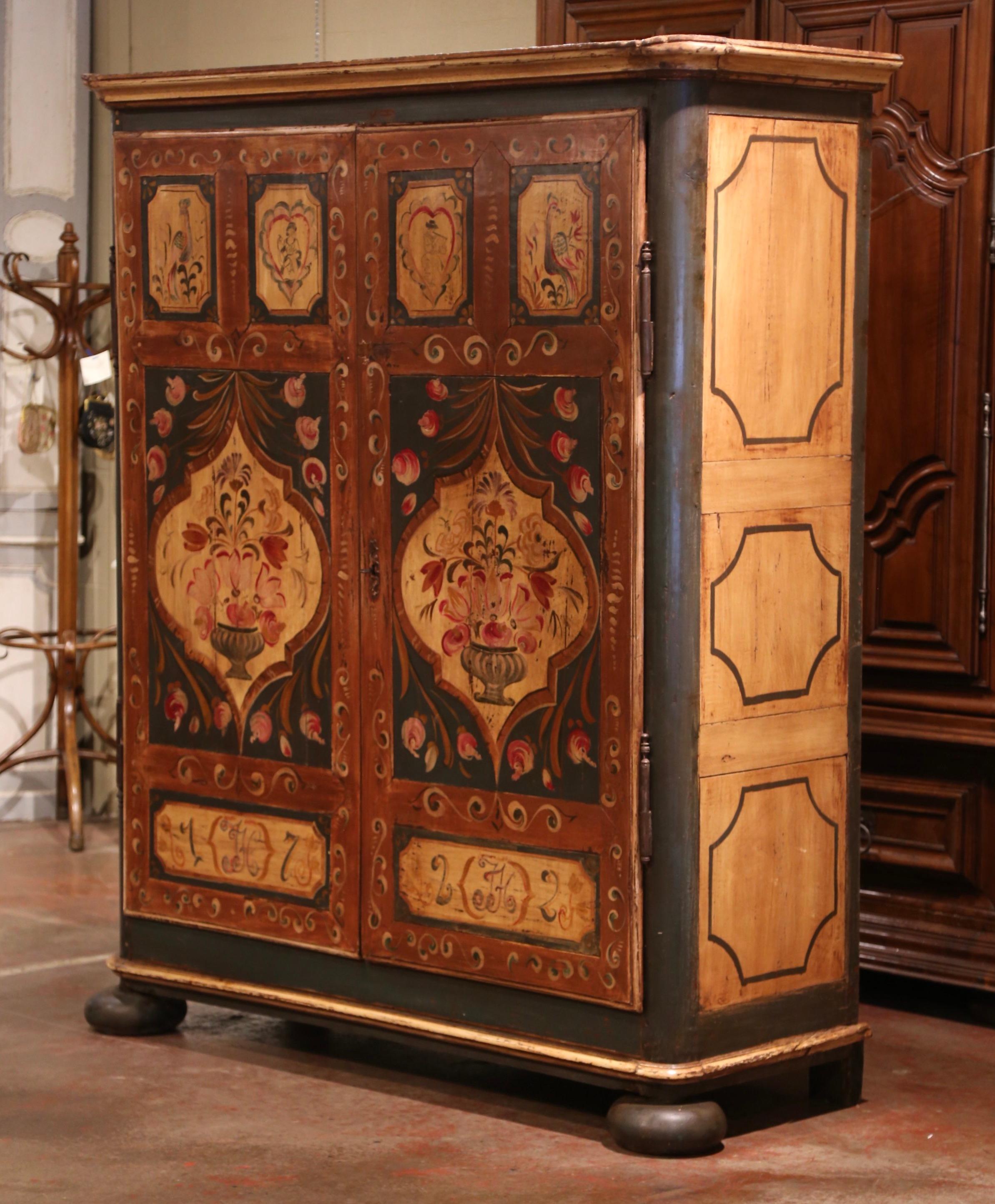 Hide your TV in this large and colorful painted antique armoire. Crafted in the Alsace Lorraine region of France circa 1820, the cabinet stands on front bun feet over a straight apron, and features a top decorative crown. The wardrobe is dressed
