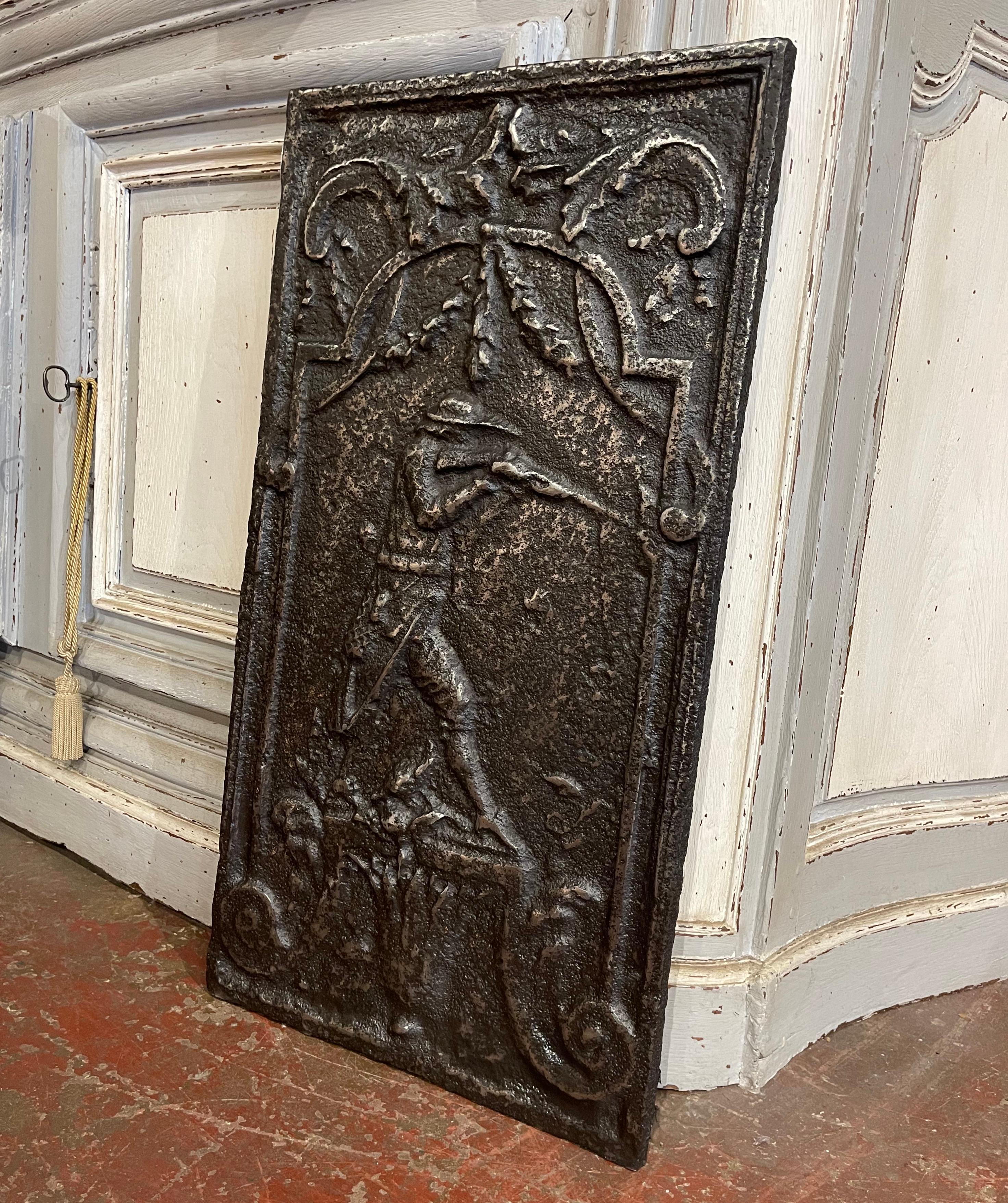 Decorate a wall or fireplace in a hunting lodge with this thick antique fire back guard. Created in France circa 1850, and in rectangular in shape, the tall plaque depicts a hunt scene with a hunter aiming his rifle, surrounded by intricate scroll