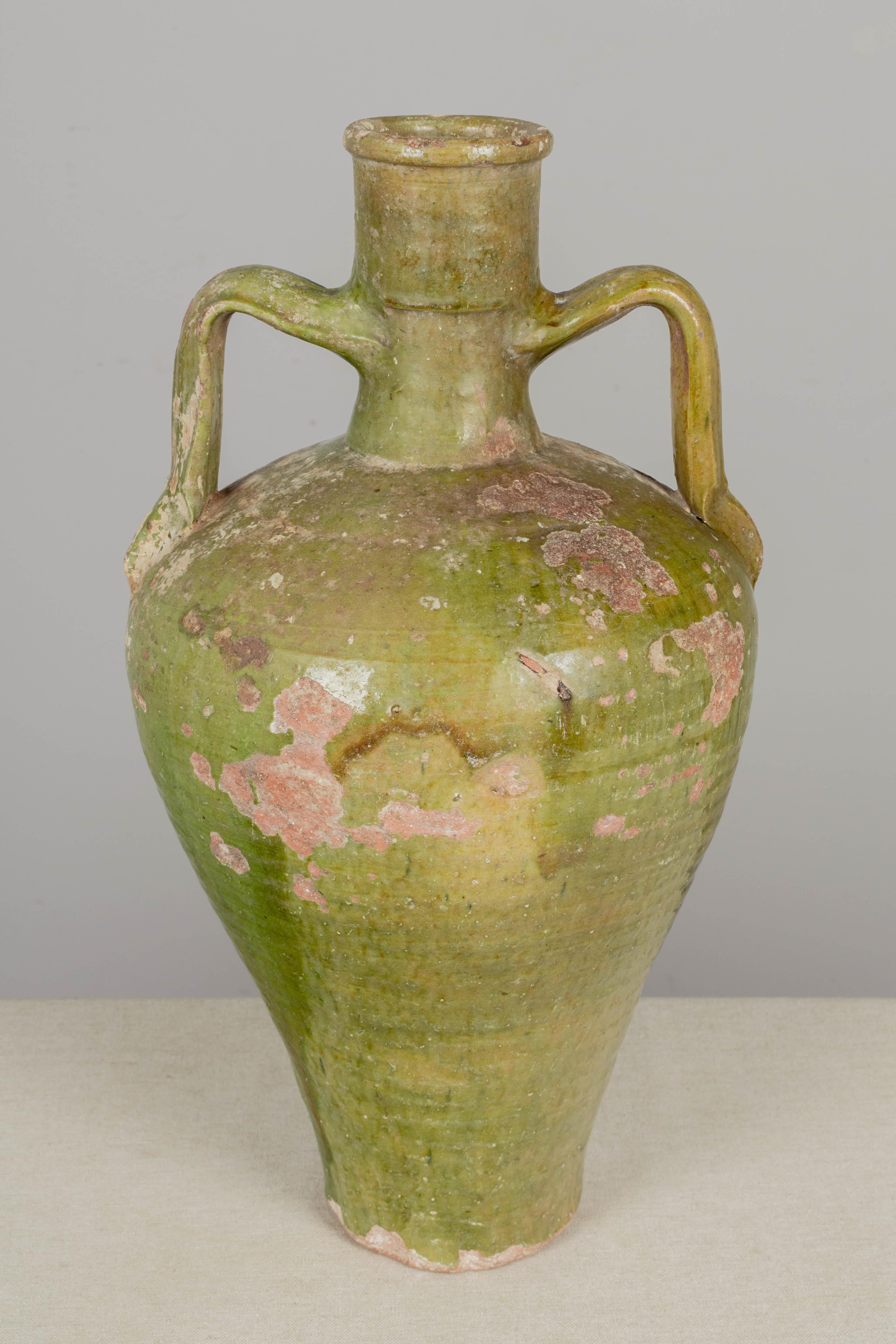 An early 19th century French green glazed terracotta double handled water jar from Auvergne. Nice old patina with patches of glaze loss. Circa 1820-1830. 
18.5