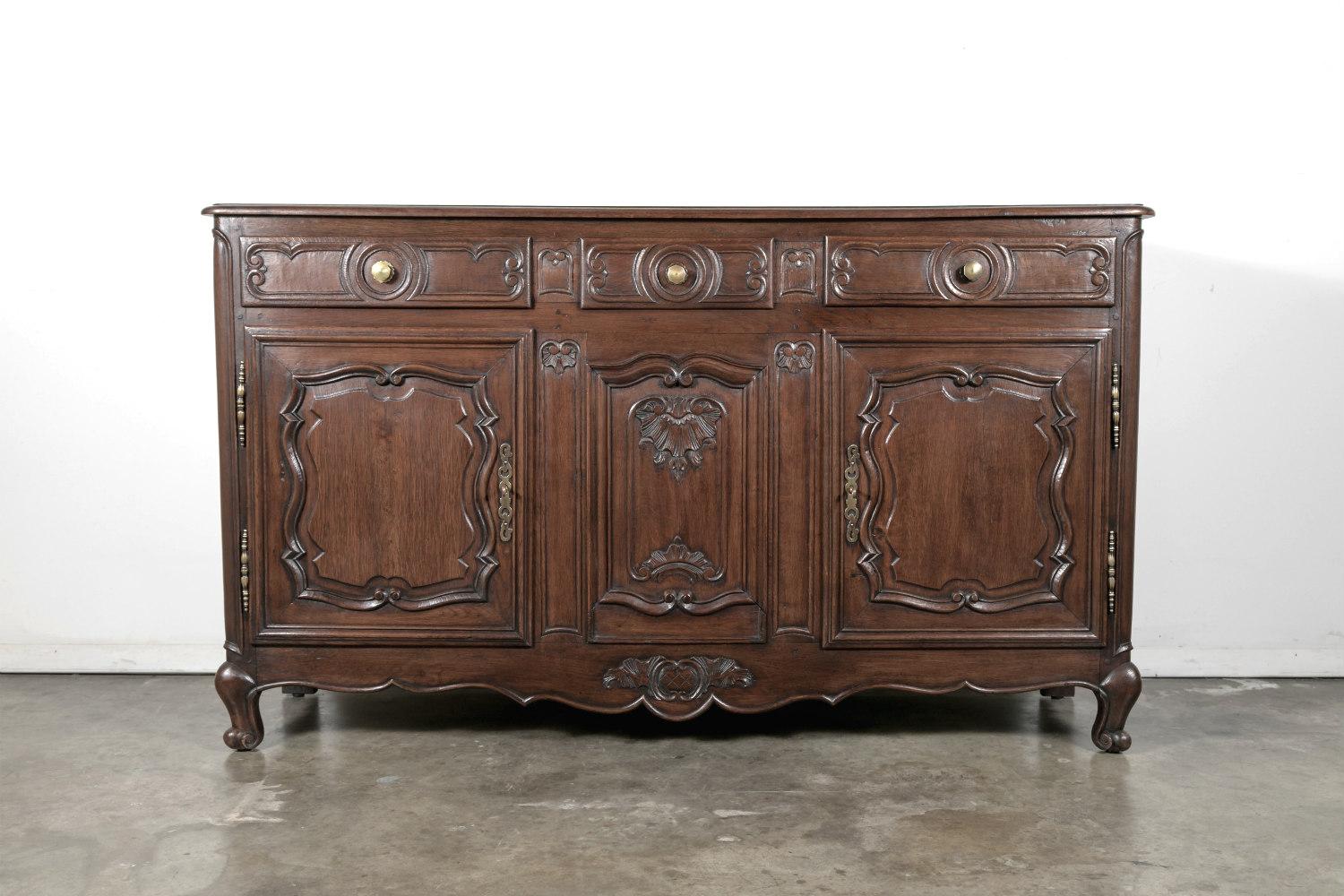 Stunning early 19th century French Provençal Louis XV style enfilade, handcrafted in solid oak by talented artisans near Avignon. This beautifully carved buffet has three carved drawers over two molded paneled doors with S-scrolls that open to