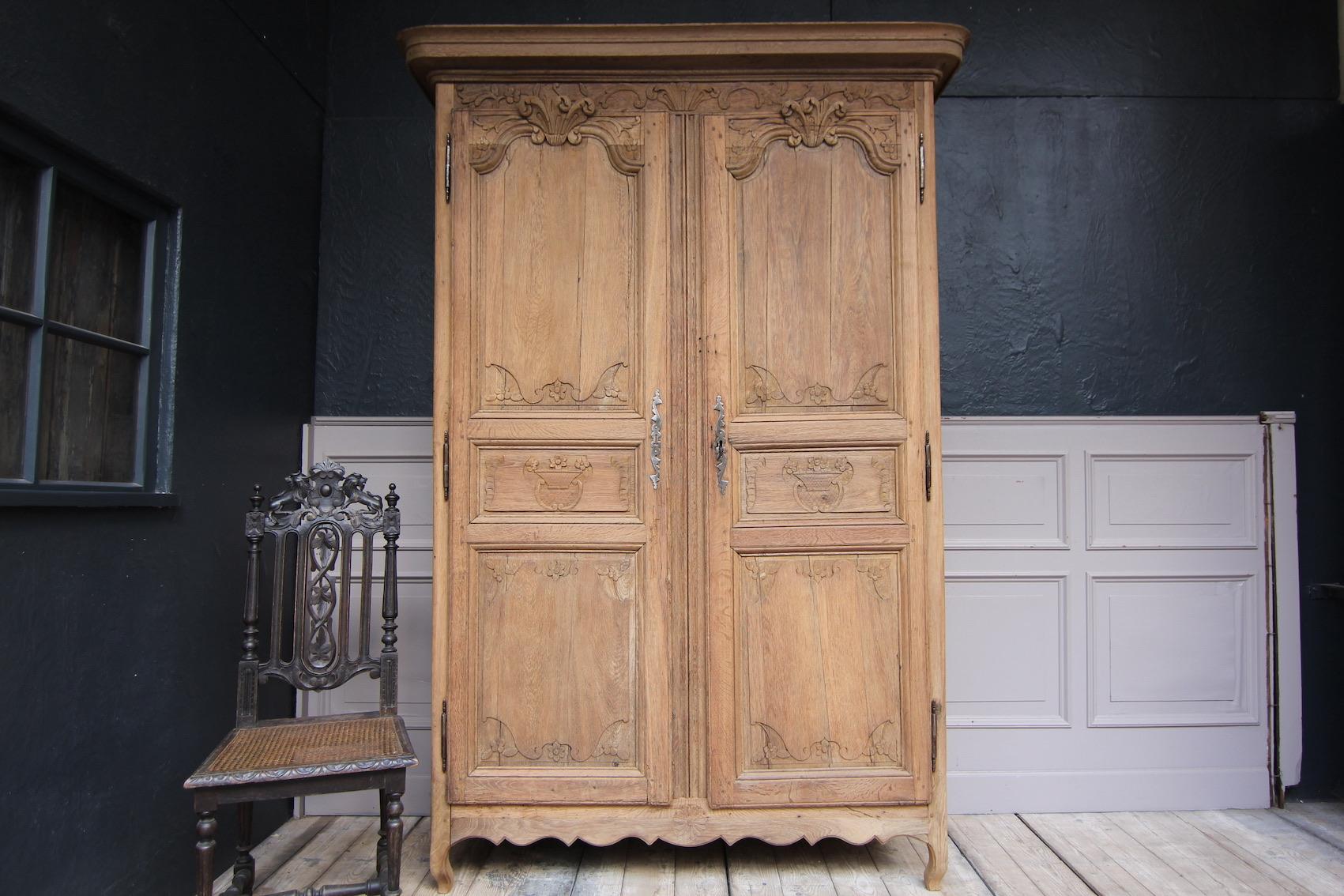French Provincial armoire or wedding cabinet from the early 19th century. Stripped of the old wax, revealing the beautiful surface of the raw partially carved oak wood.

A two-door side coffered body with applied moulded cornice. The doors are