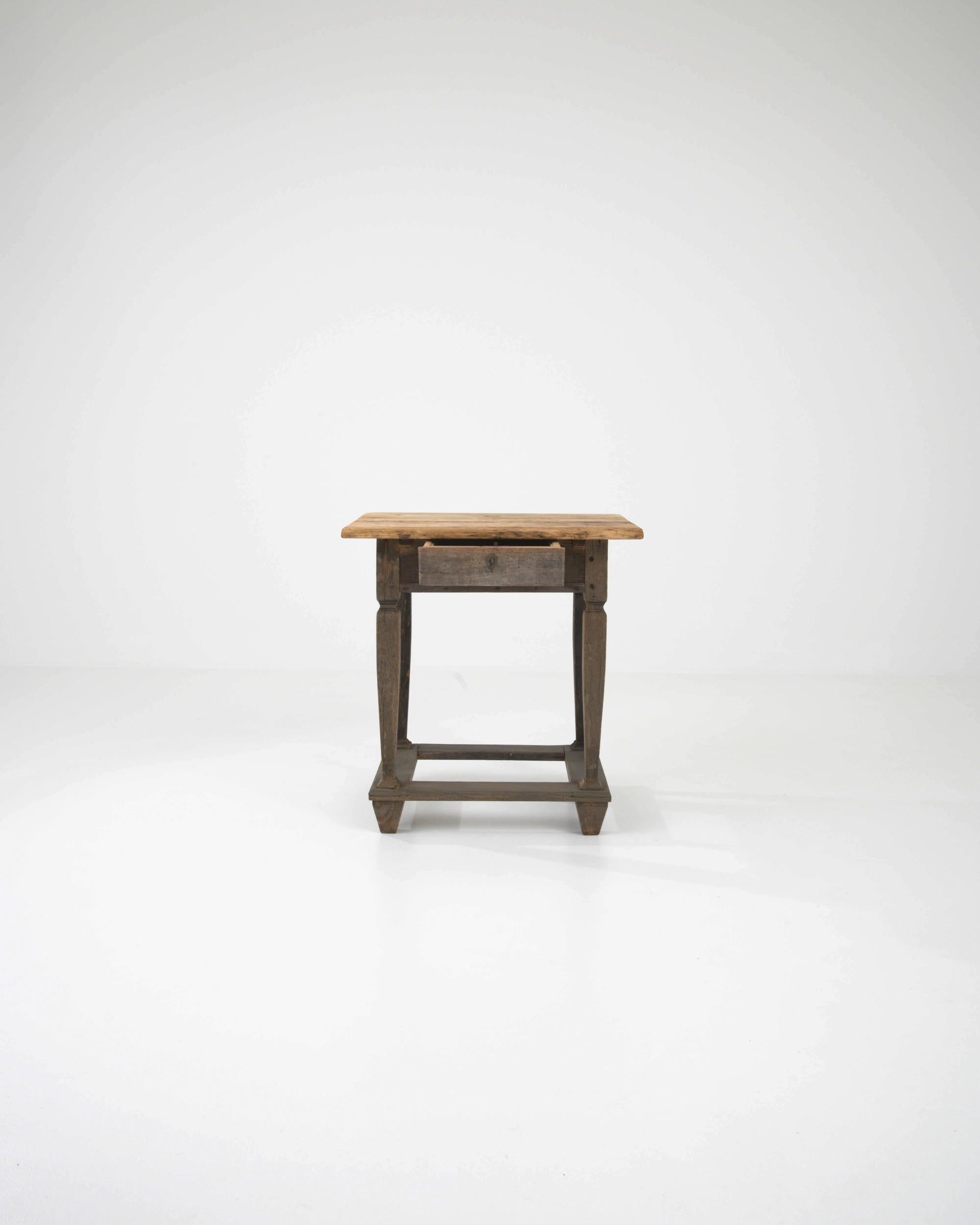 This antique wooden side table offers a delightful Provincial find. Made in France in the early 1800s, the silhouette is simple yet full of personality: chunky pyramidal feet are counterbalanced by slender, gracefully contoured legs. A small drawer