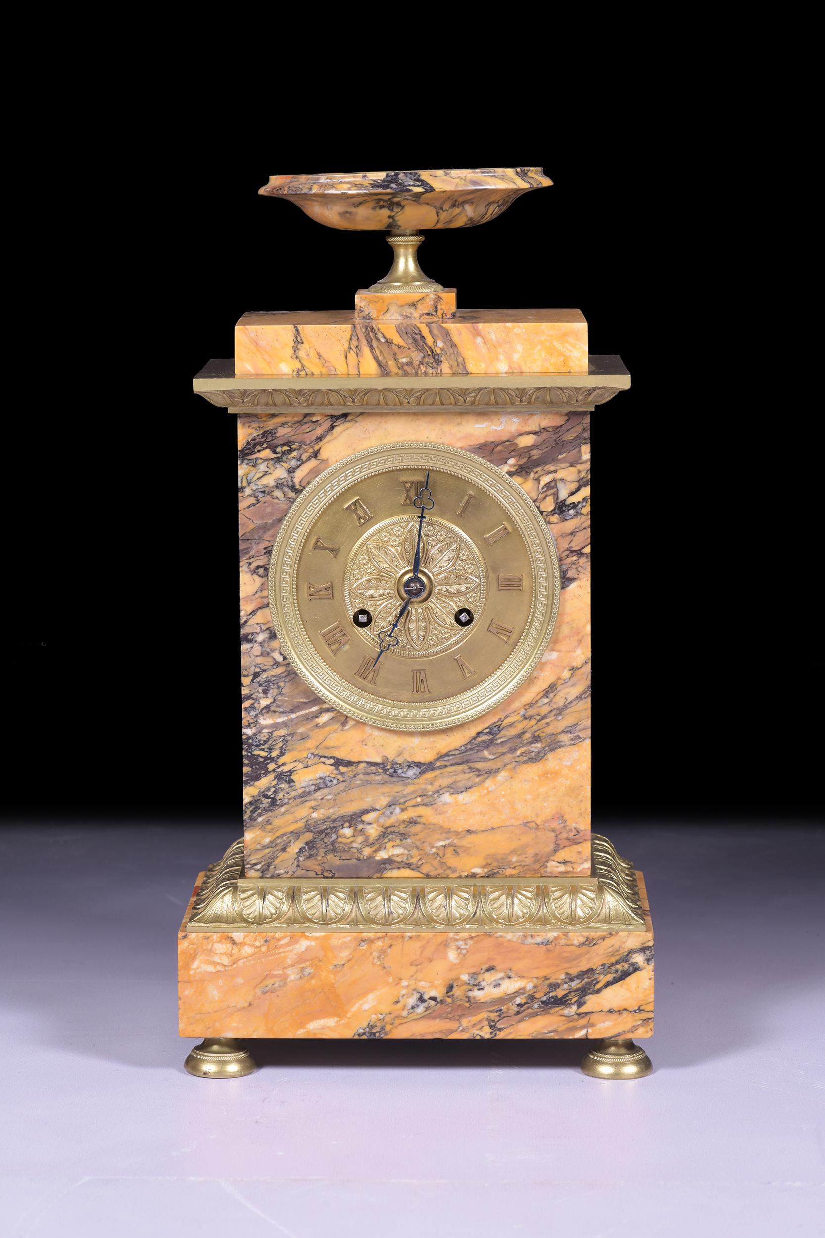 An exceptional quality early 19th century Sienna marble and ormolu mantle clock, the sienna marble case surmounted by an urn, raised on ormolu bun feet and a rectangular plinth steeped base with foliate cast border, the gilt dial is surrounded by a
