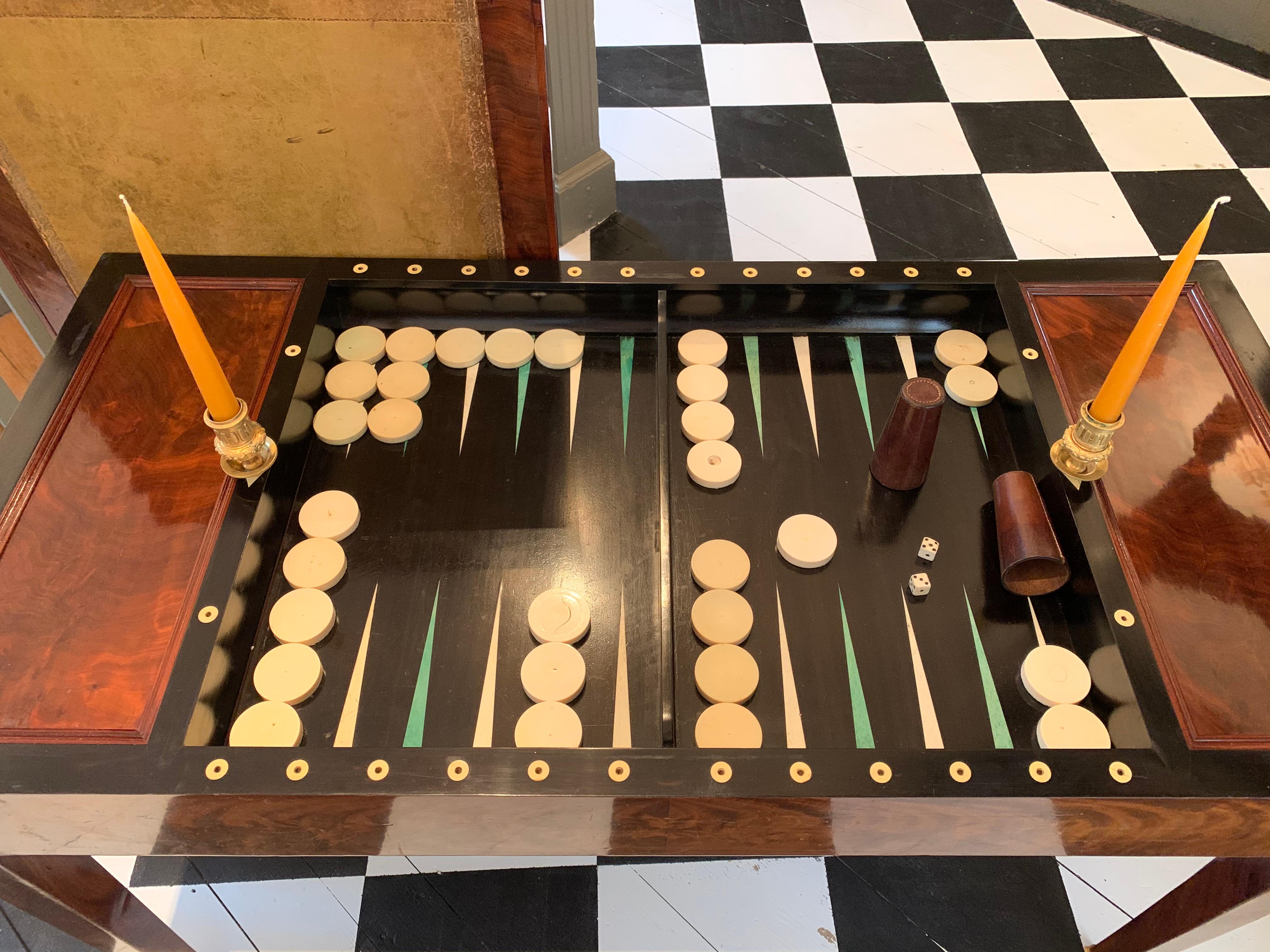 Early 19th century mahogany Tric-Trac or Backgammon table. Original base and leather covered top. Opens to reveal ebony and bone inlaid backgammon well. Draughts and Candlecups. Top flips to provide felt for card playing on one side and leather for