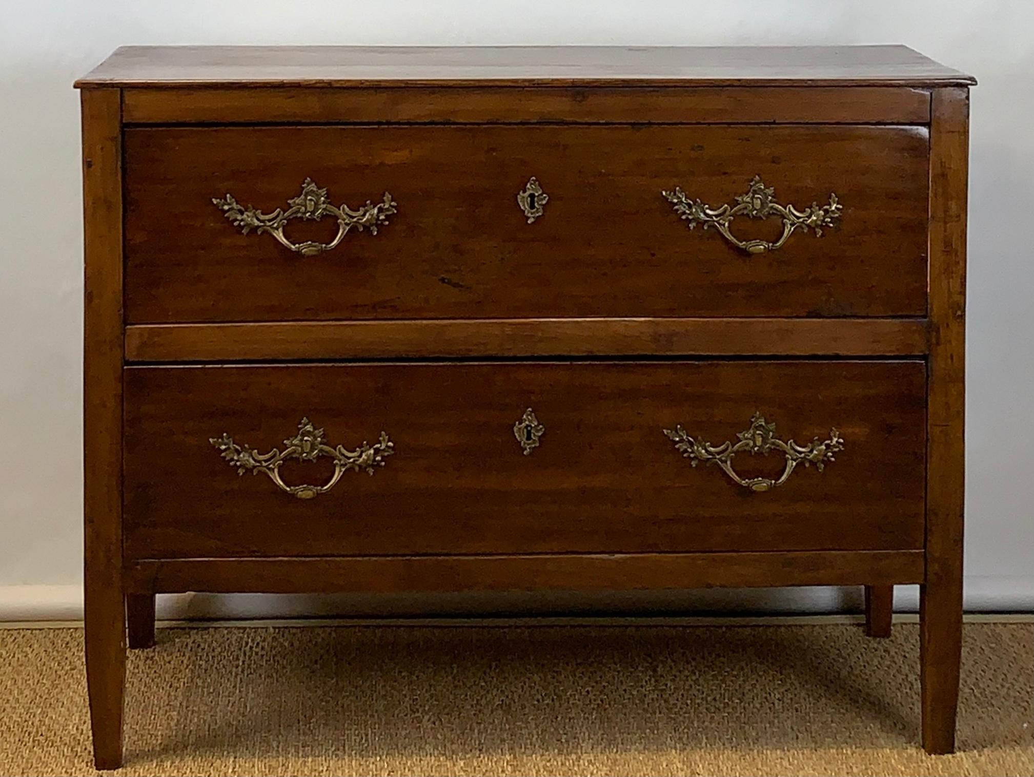 A simple and elegant early 19th century French fruitwood two-drawer commode with early hardware resting on square tapering legs.