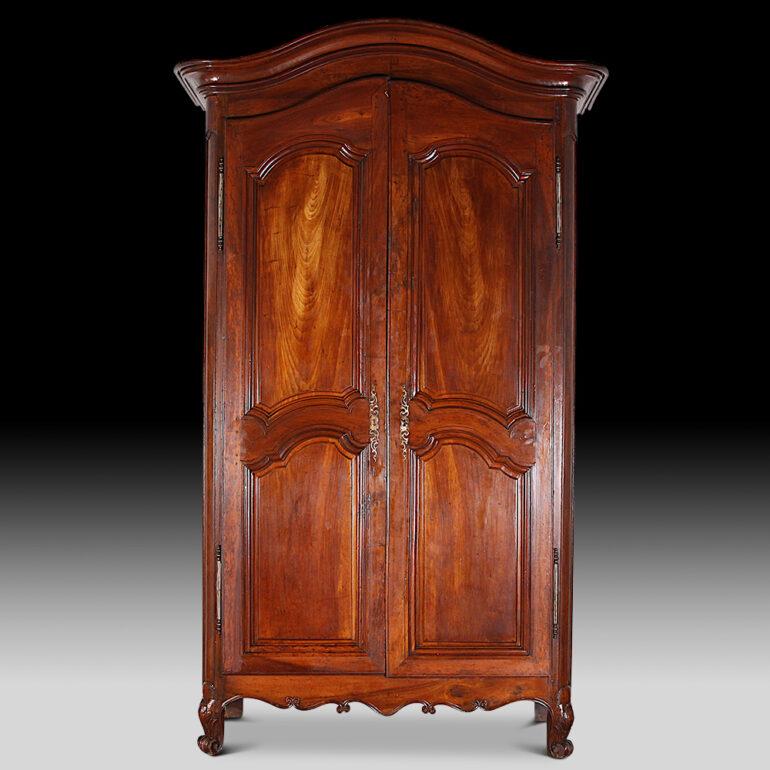 Early 19th century French walnut armoire with shaped panelled doors and sides. Beautiful colour and patina and with the original hardware and lock / key. C. 1820.