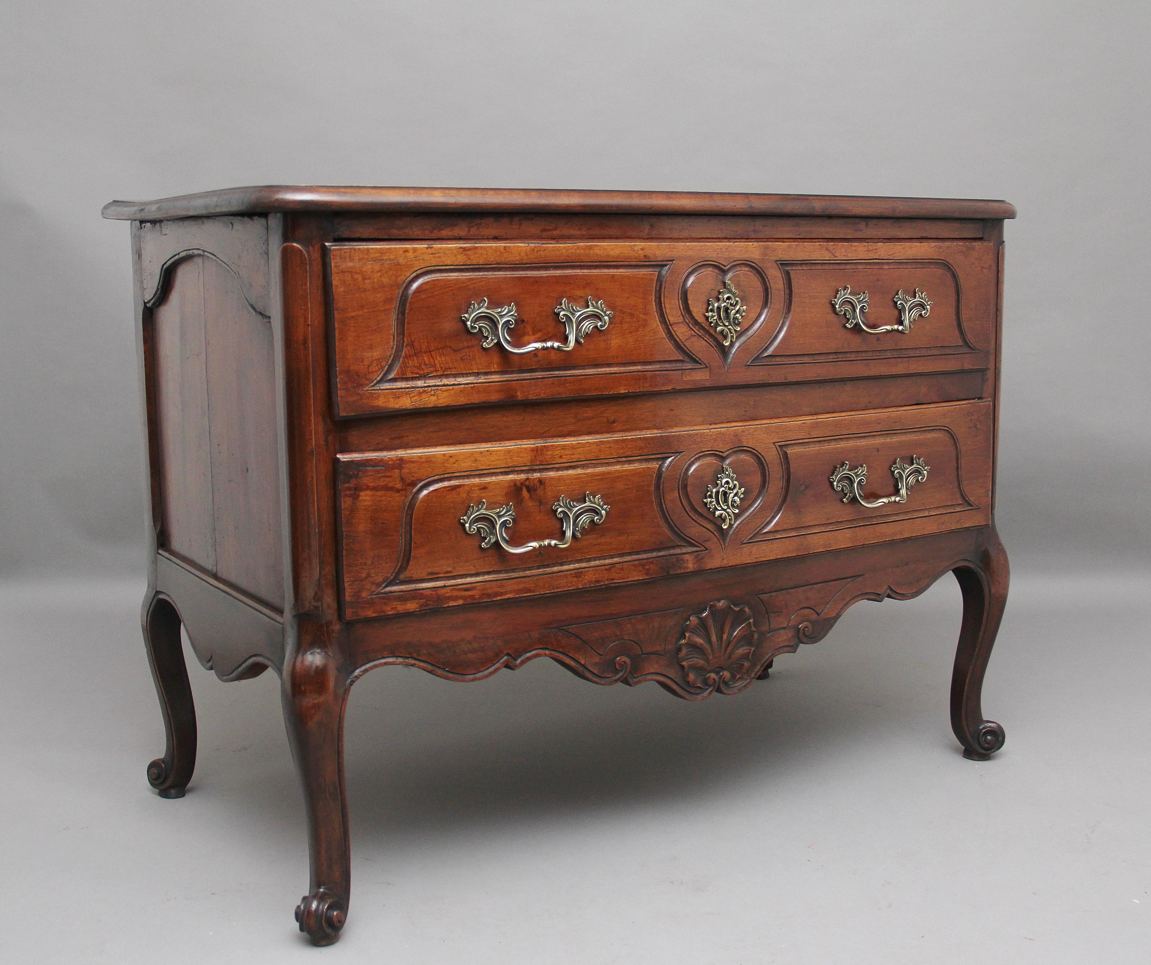 Early 19th century French walnut bow front commode, the shaped moulded edge top above two deep drawers with original brass handles and escutcheons, the drawer fronts having heart shaped incised ornament, shaped conforming frieze below with carved