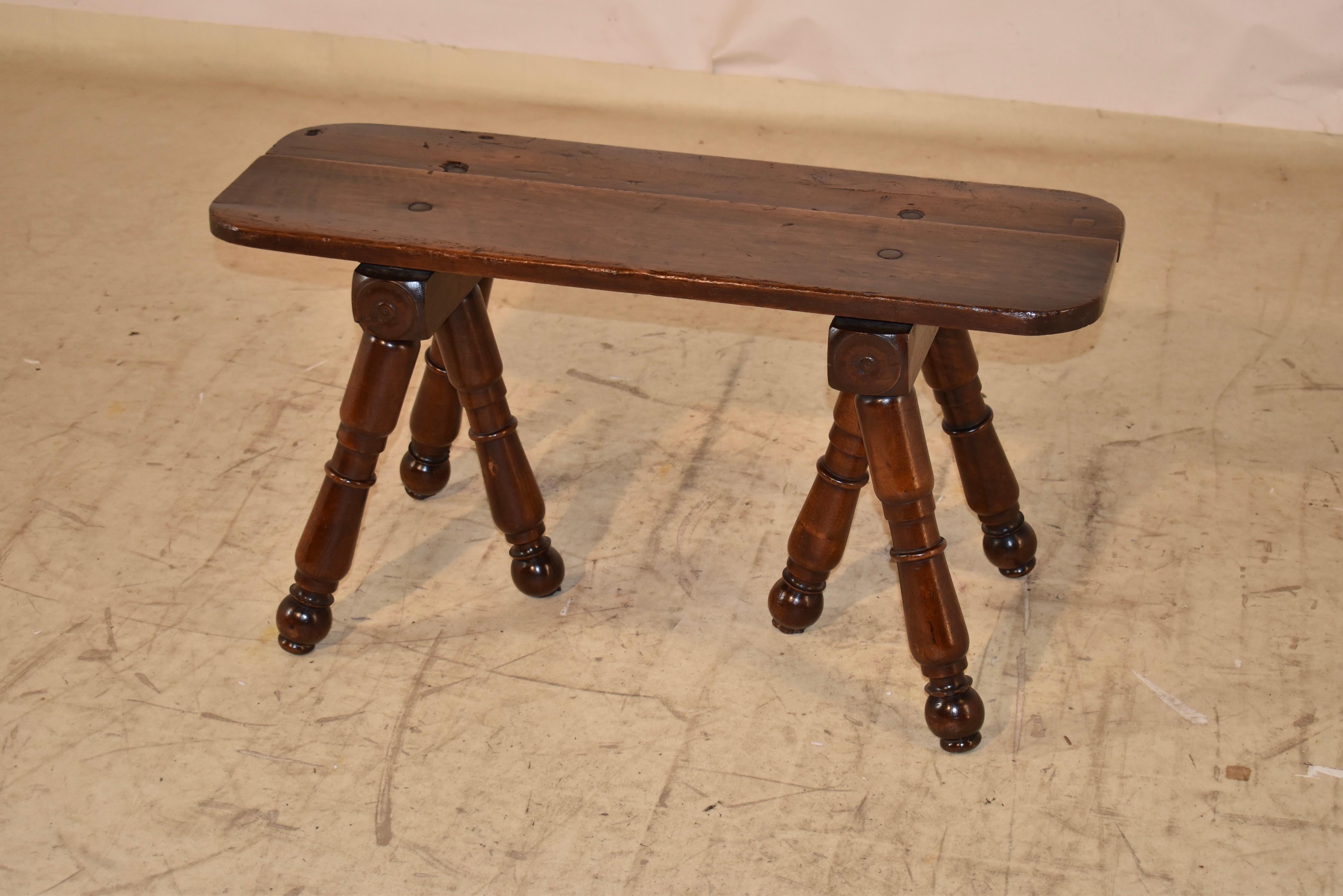 Banc d'art populaire français en noyer du début du 19e siècle.  Le siège est fabriqué à partir de deux planches aux coins arrondis.  Le siège repose sur deux supports, tous deux dotés de trois pieds tournés à la main.  Il s'agit d'un banc d'art