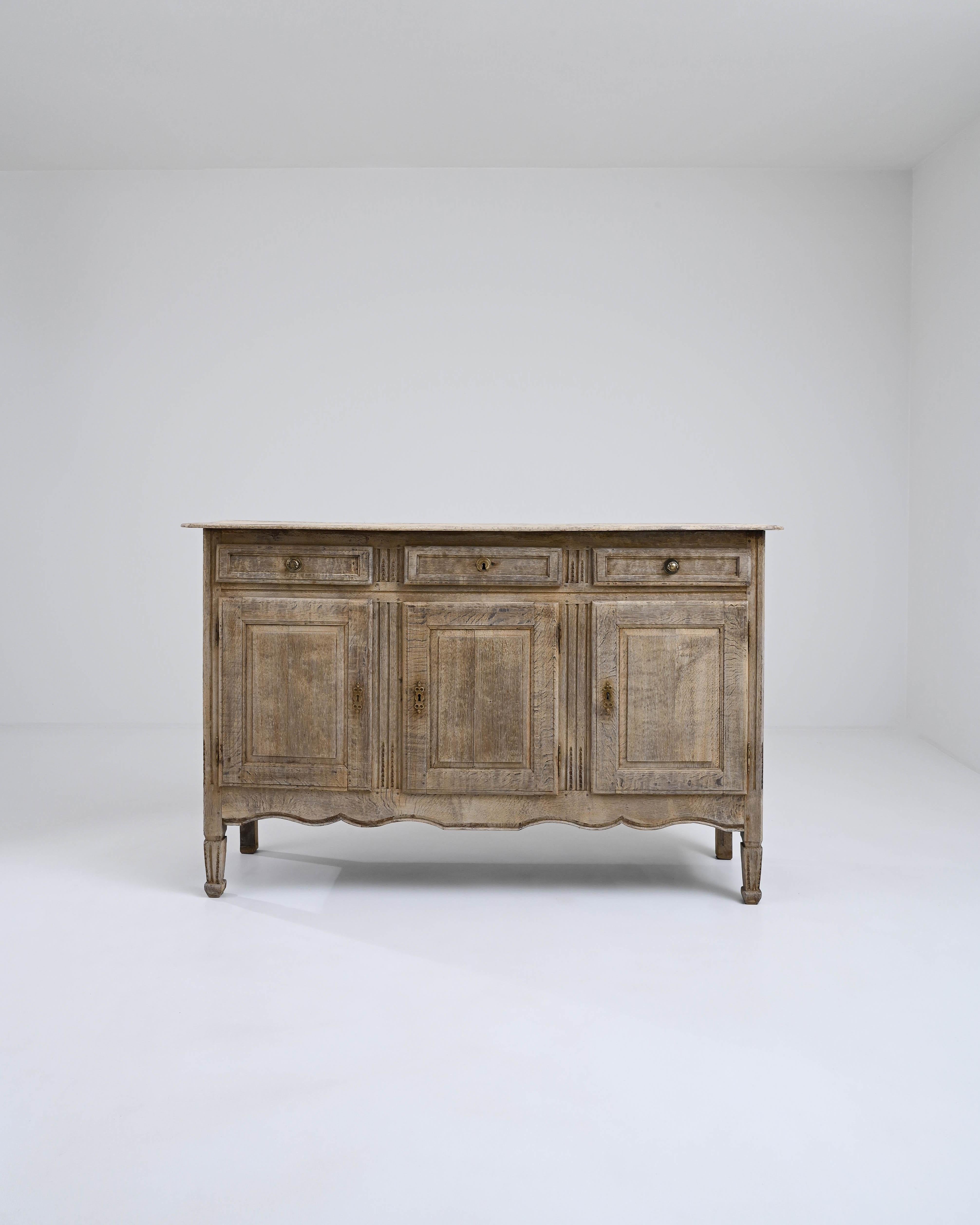A wooden buffet made in early 19th century France. This French buffet presents a picture of high craft and delicately imparted details. Gestures such as the notched feet, brass keyholes, and tapering carved aprons cast a spell of special charm. A