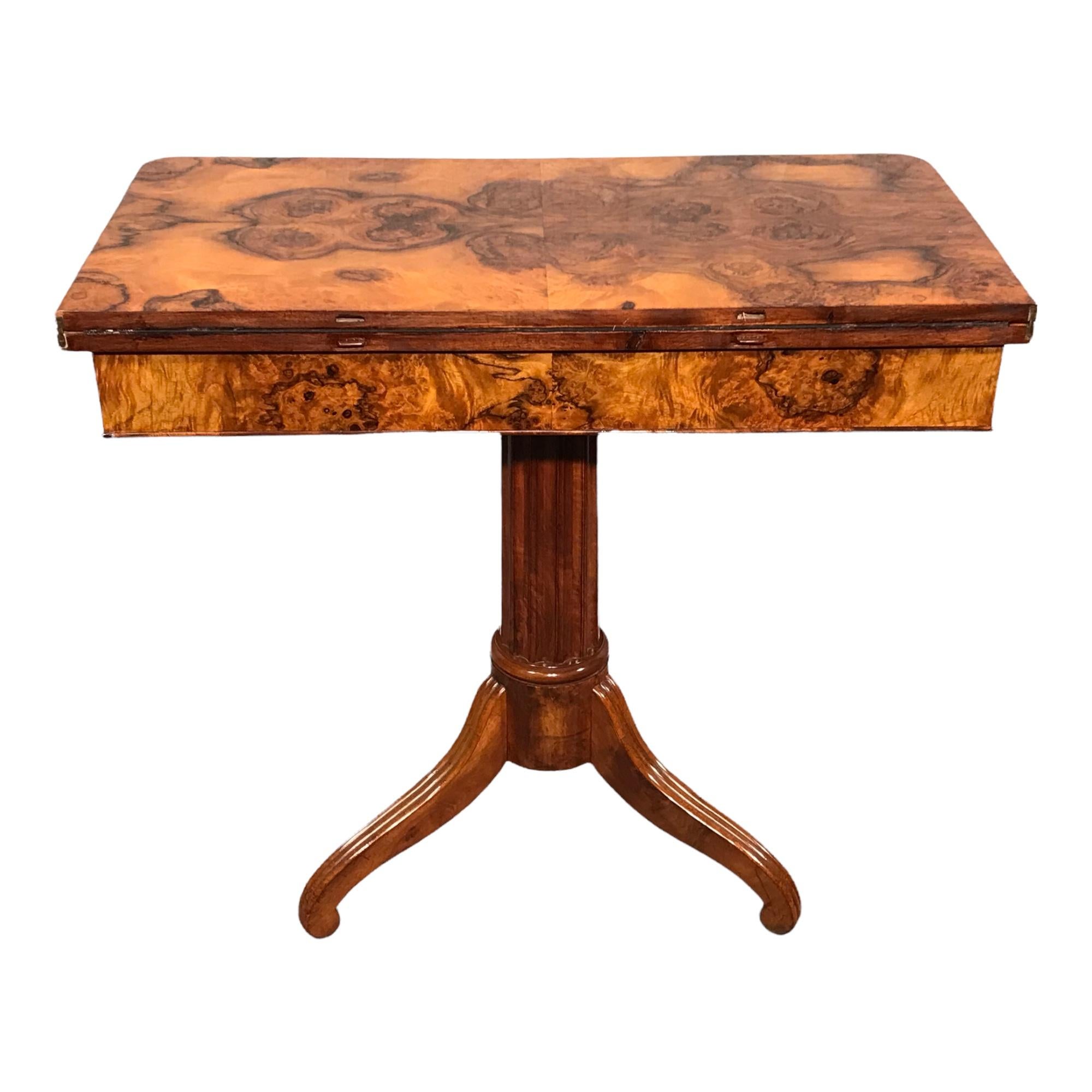This unique game table dates back to the early phase of the Biedermeier period. 
It comes from Southern Germany. The game table has a beautiful walnut root veneer on top and apron. It stands on a central fluted column foot with a tripod base. The