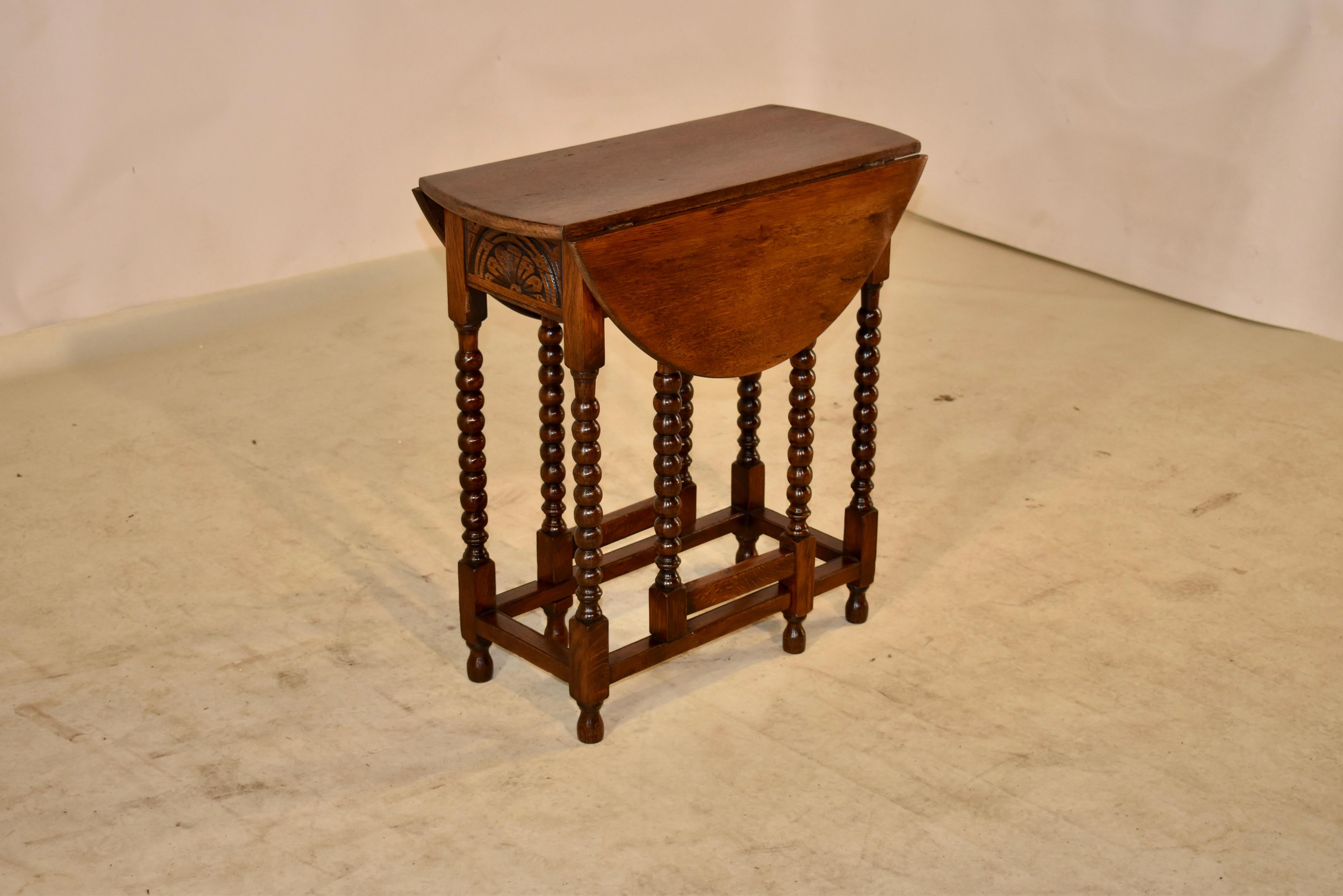 Early 19th century oak gate leg table from England, circa 1800. The top and leaves are made from single boards with pegged construction, over hand carved decorated aprons. The table is supported on hand carved bobbin legs , which are joined by