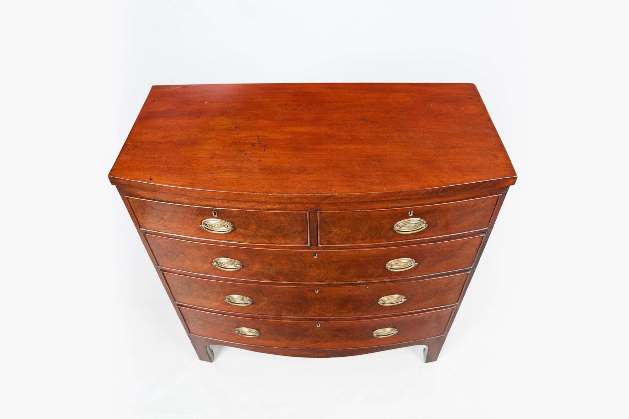 Early 19th century George III flame mahogany bowfront chest, the moulded top raised above two short and three long cockbeaded graduated drawers with decorative brass pulls with foliate motif and escutcheons raised above shaped apron terminating on