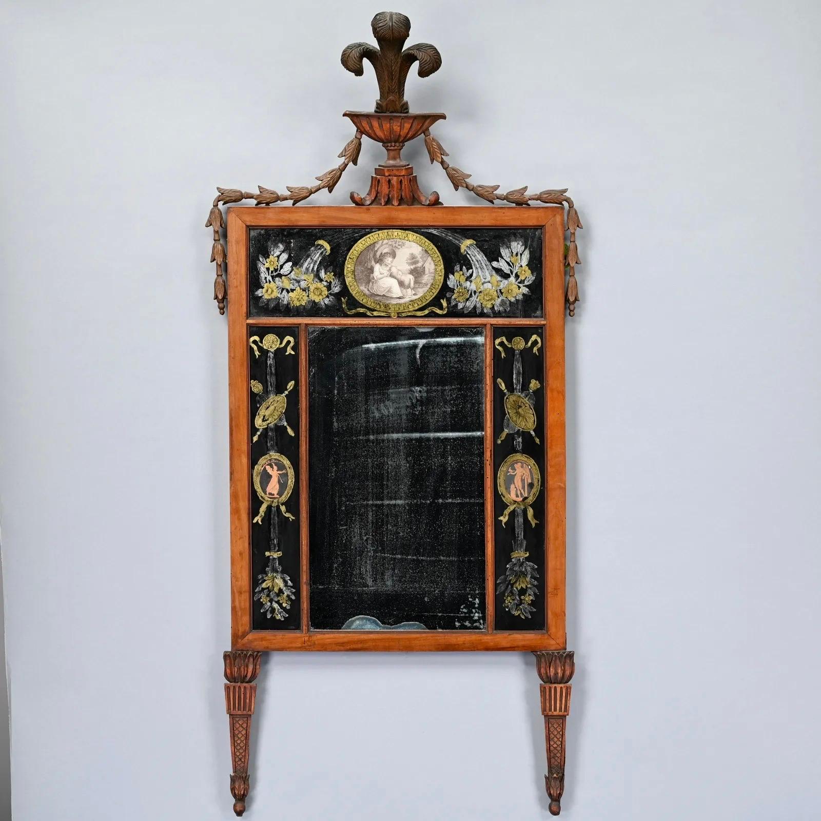 Early Nineteenth Century George III or Regency Eglomise Mirror of Carved Beechwood. The rectangular mirror plate flanked by eglomise panels of tassels, each hung with medallions of trophies and classical figures, surmounted by an eglomise panel