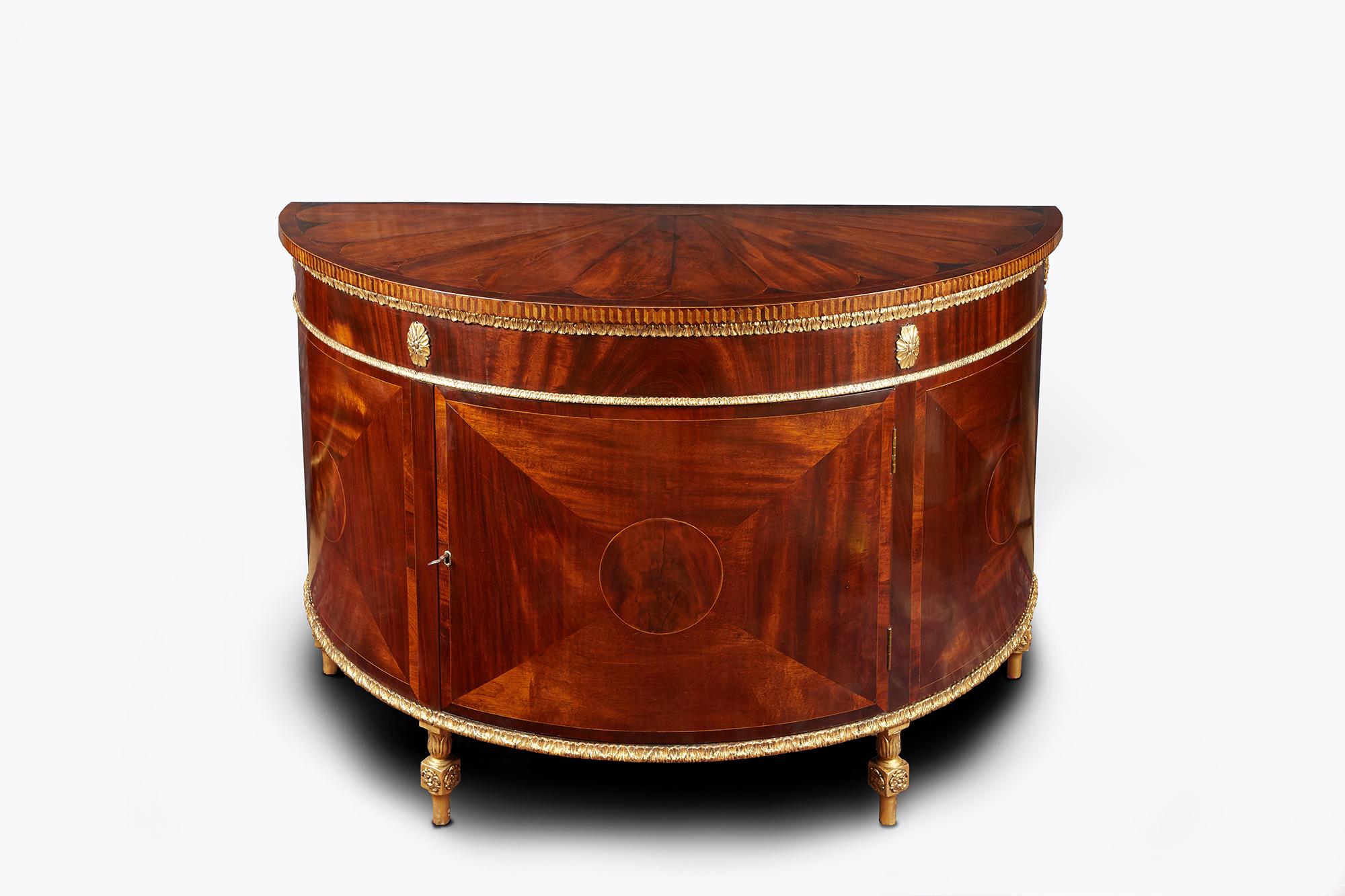 Late 18th century George III pair of flame mahogany demilune commodes, the moulded top with foliate shaped fan inlaid with boxwood and fruitwood and crossbanded in rosewood, trimmed with parquetry rim raised over parcel gilt frieze with egg and dart