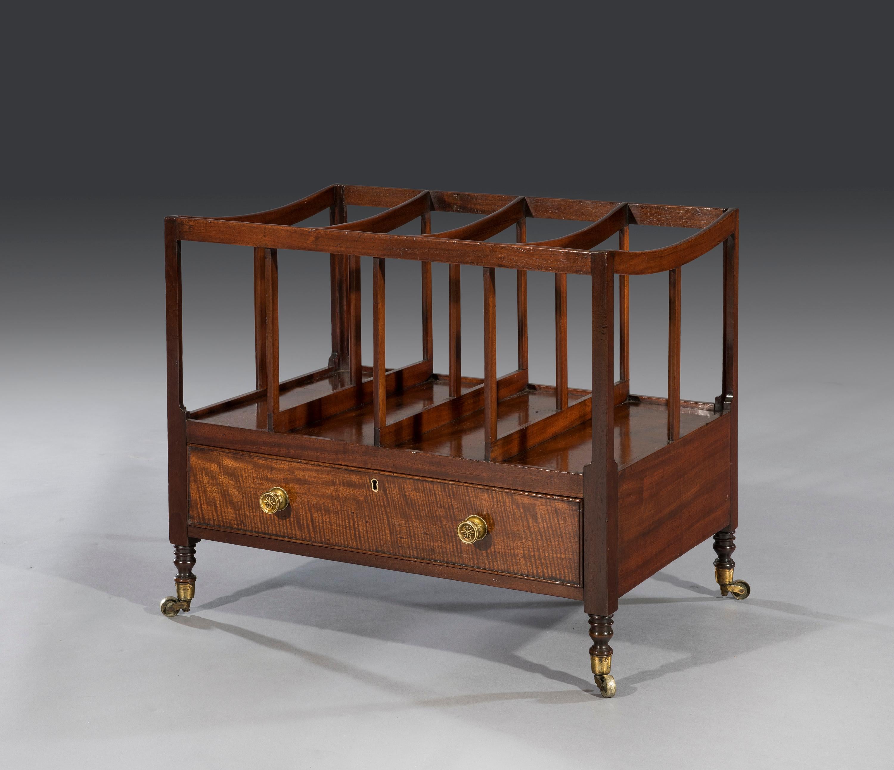 The oversized Canterbury is of elegant proportions with four divisions above a figured mahogany drawer. The Canterbury stands four turned legs and terminates on the original brass castors.