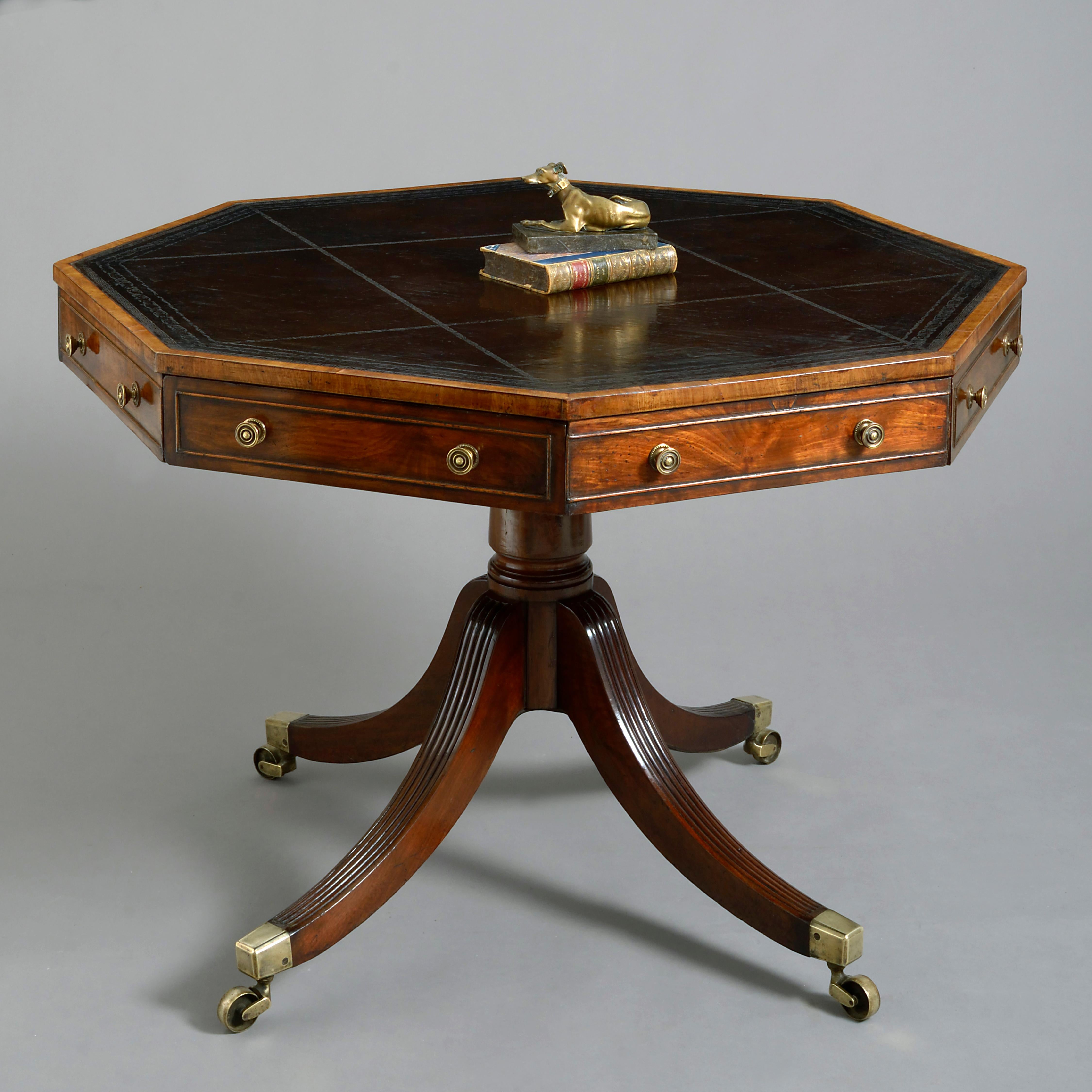 A fine early 19th century mahogany rent table of octagonal form, the black tooled leather writing surface upon a frieze of four drawers articulated by four four dummy drawers each with circular brass handles, all raised upon a turned stem with four