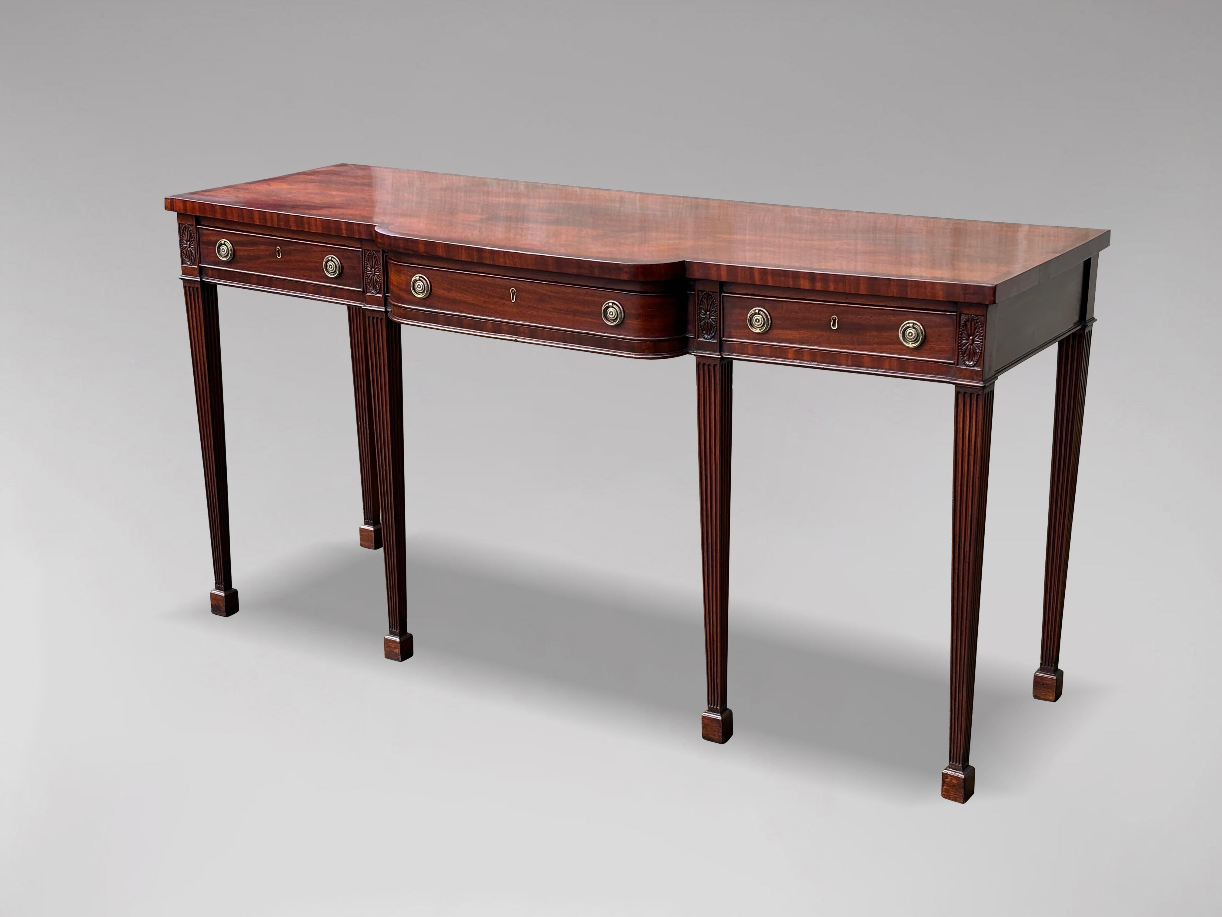A wonderful early 19th century, George III period mahogany rectangular breakfront serving table or sideboard. The crossbanded top is made from a single section of figured mahogany which runs the whole length, above one long centre drawer flanked by