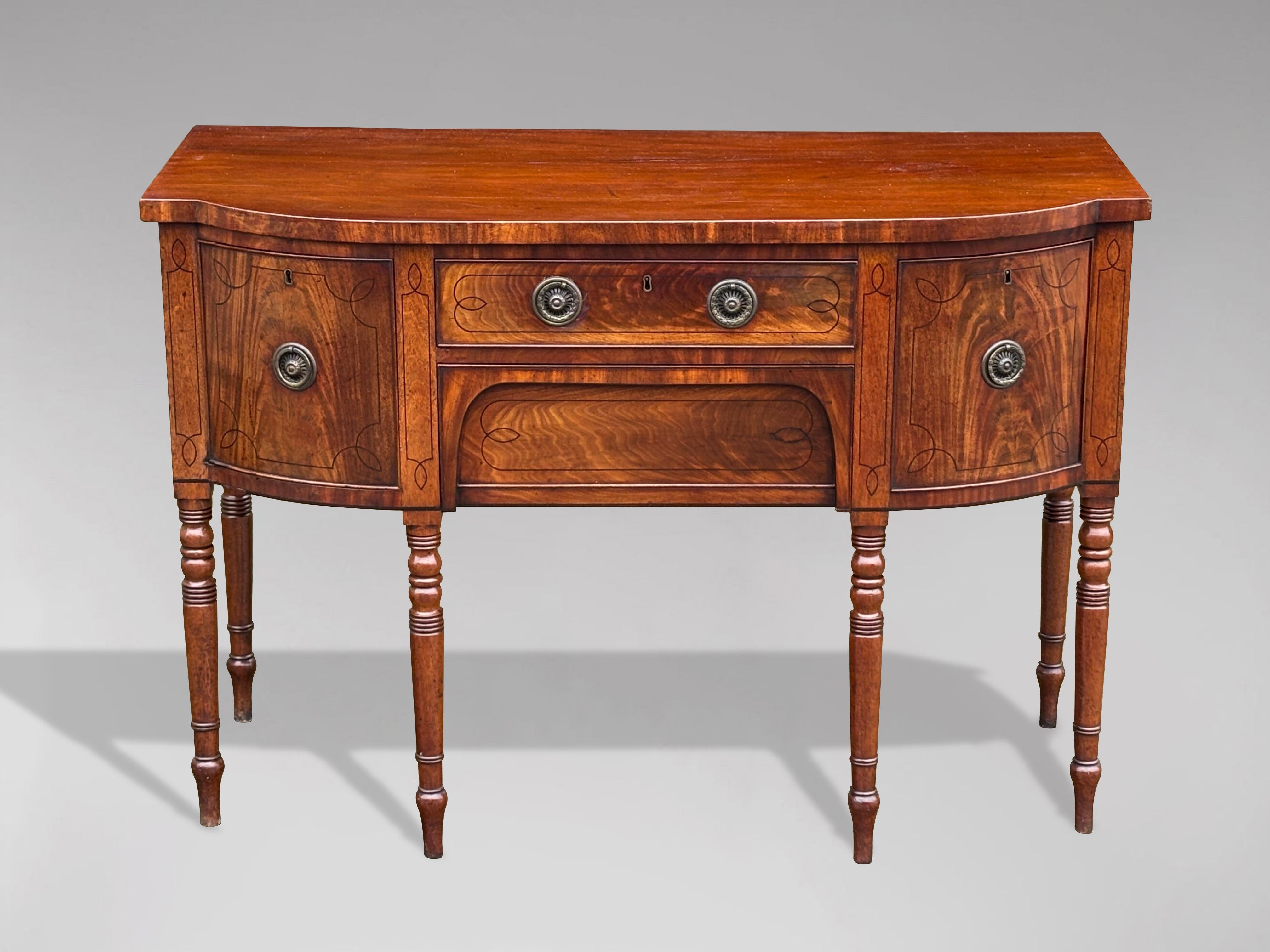 An early 19th century, very fine George III period solid mahogany and ebony inlaid bow front sideboard. This Georgian period breakfront sideboard features a central frieze drawer, with an apron drawer below, flanked by a further deep drawer and