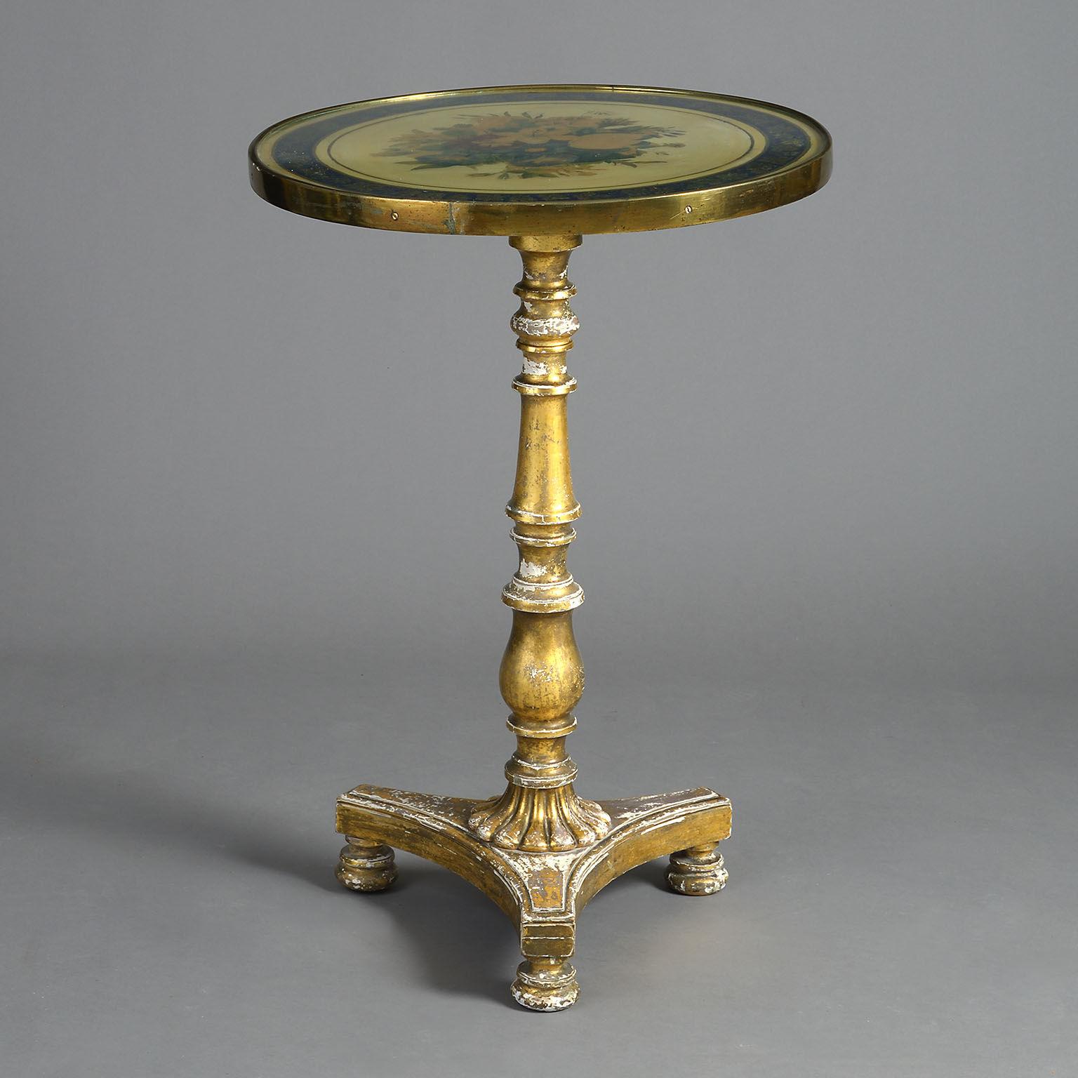 The hand-painted floral top protected under glass with a lacquered brass border. The tilt-top action supported on a gilt-wood baluster turned support with a platform base. Bearing a makers label 