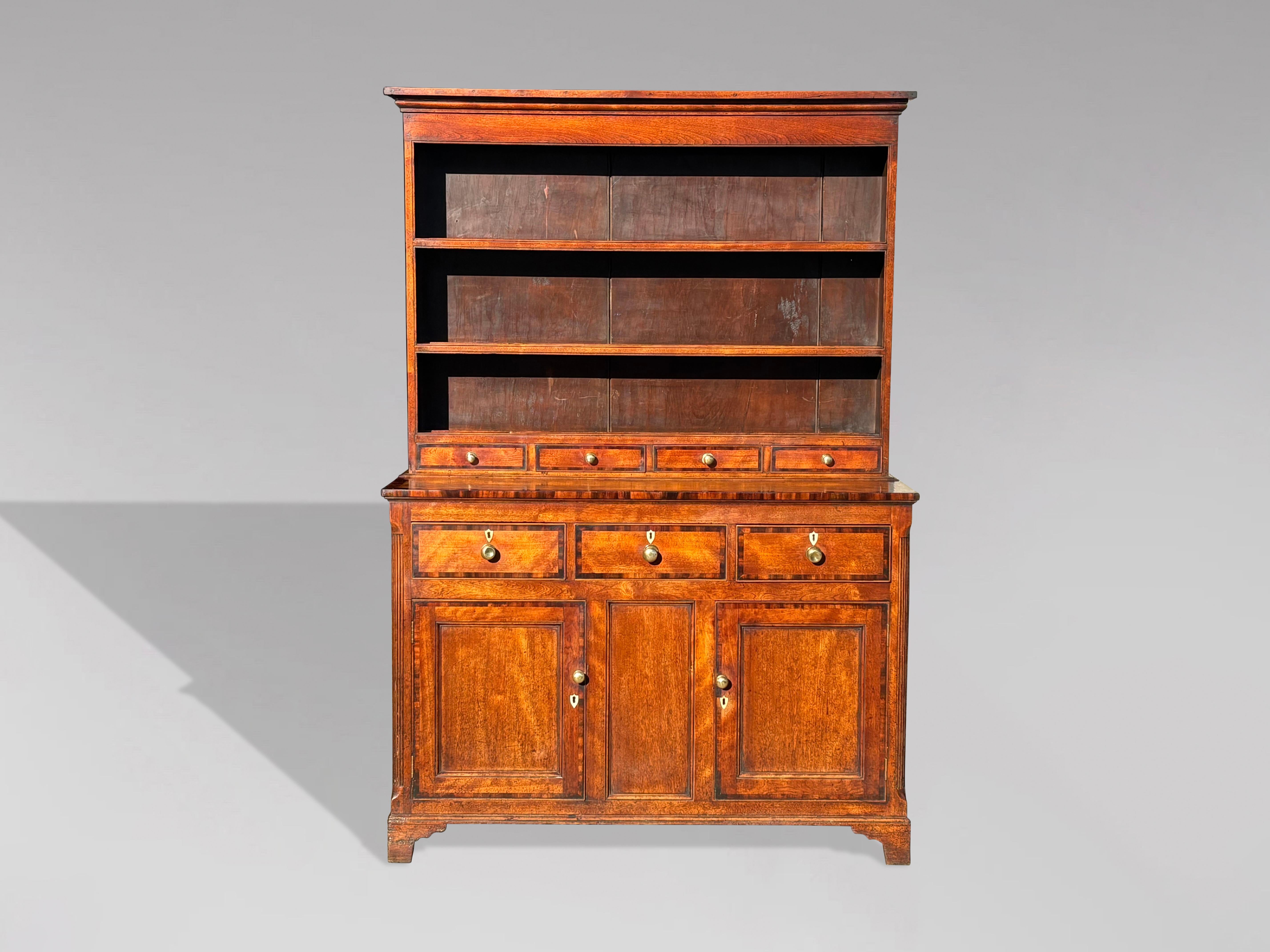 A charming early 19th-century, late Georgian fruitwood dresser with mahogany crossbanding, showcasing a beautiful golden colour. The original boarded plate rack features horizontal shelves with raised lips to securely hold plates, topped by a