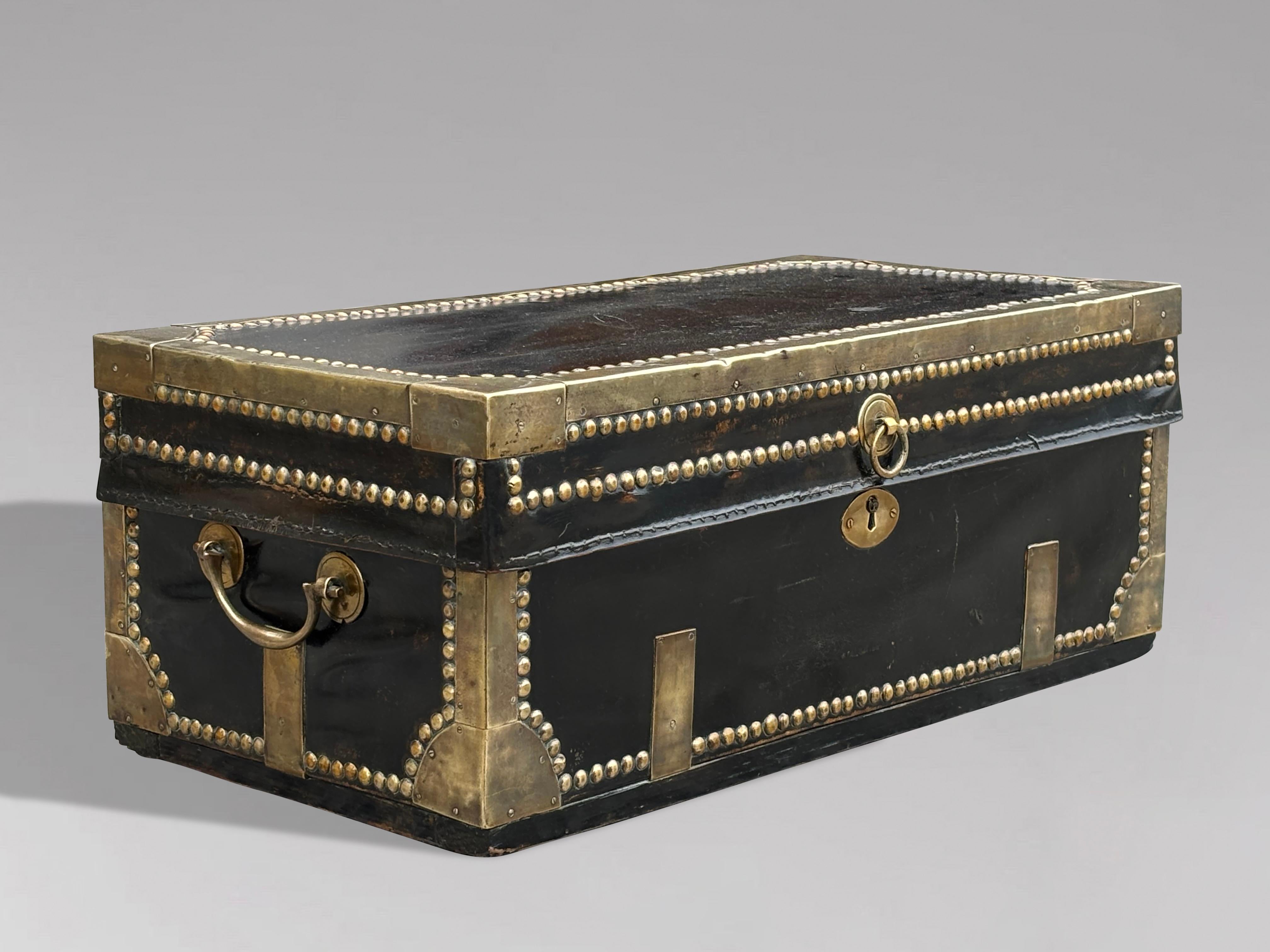 Questo piccolo e attraente baule da viaggio georgiano in pelle rilegato in ottone dell'inizio del XIX secolo è un pezzo notevole. È rivestita in pelle splendidamente borchiata e rinforzata con rilegature in ottone, con borchie in ottone a pannelli e