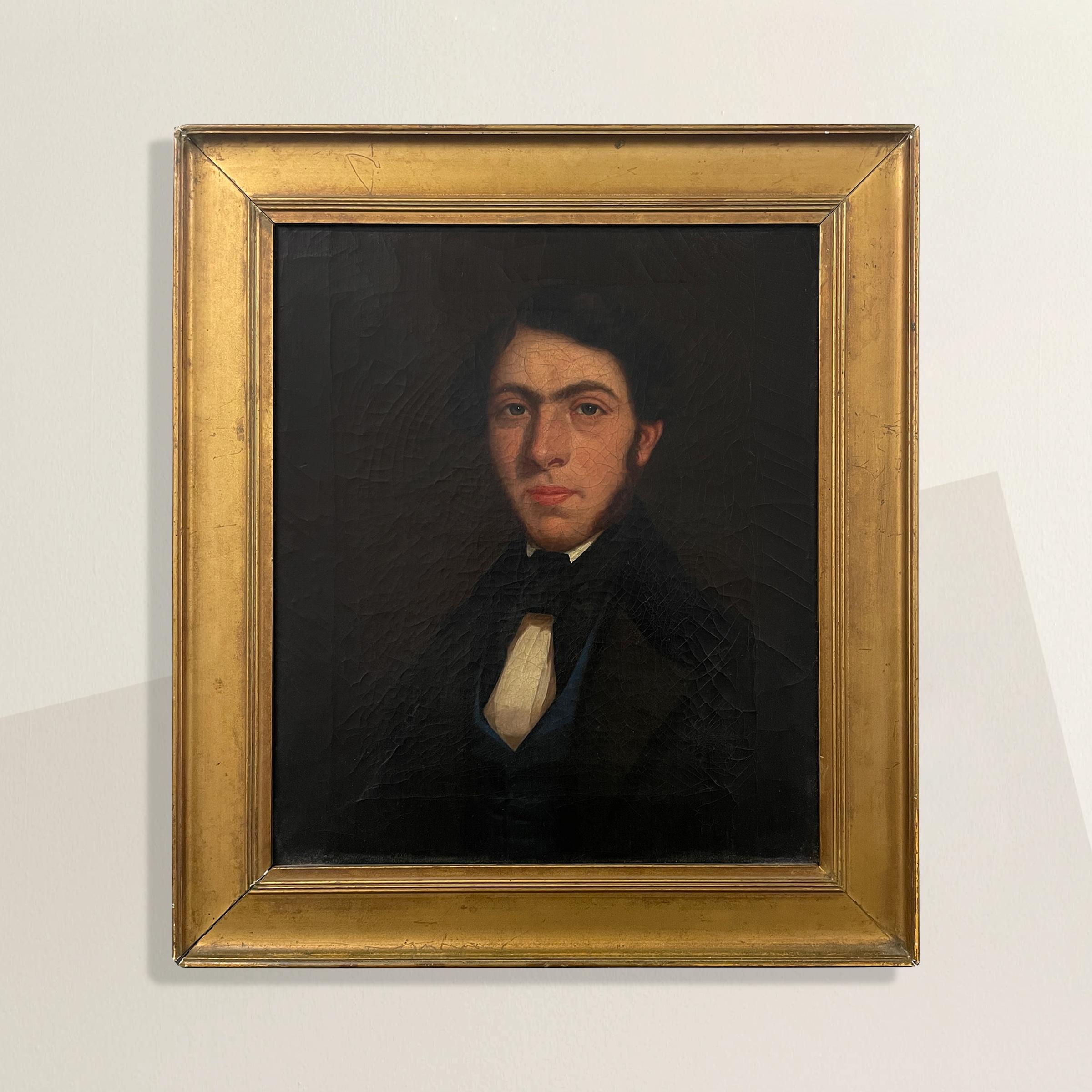 A beautiful early 19th century Georgian Regency era oil-on-canvas portrait of a gentleman with long sideburns, and wearing a cravat and blue silk waistcoat. Framed with a gilt frame.