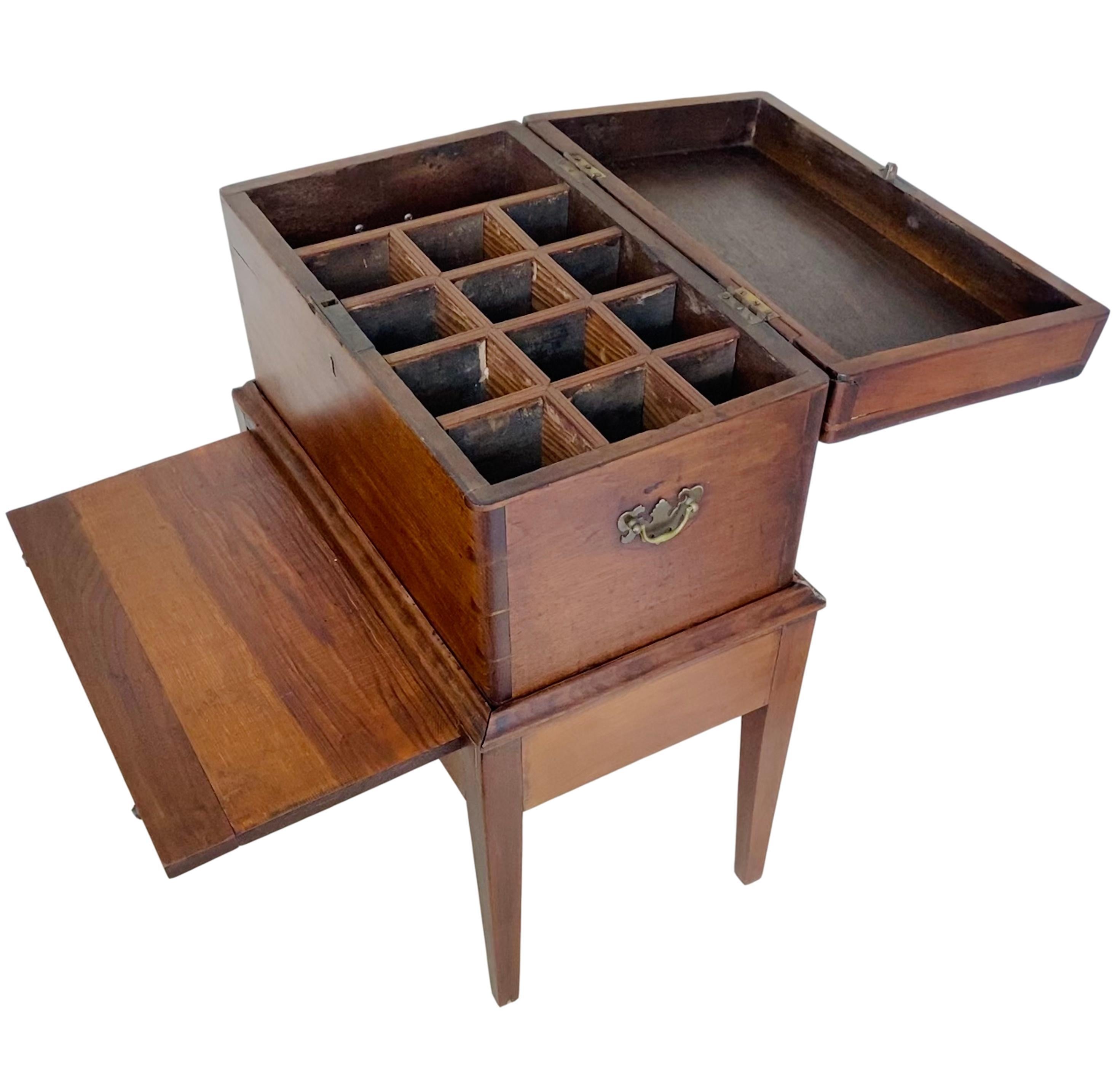 An antique early 1800's George III cellarette on stand (2 pieces). Made of heavy walnut with dovetail joinery. The interior is fitted with twelve bottle slots and one lidded compartment. The stand features tapered legs and a slide out surface. Brass