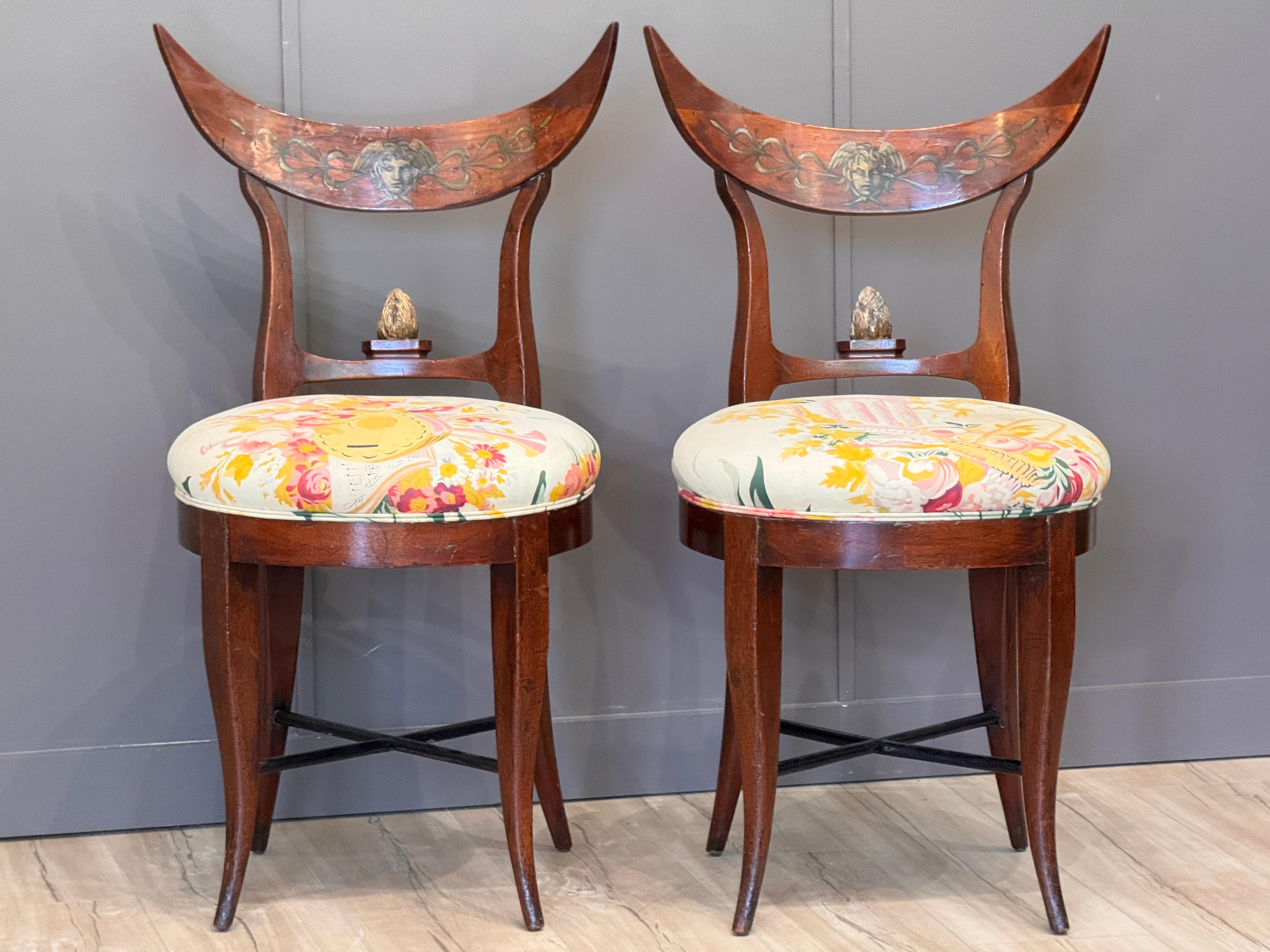 Une paire de chaises Biedermeier allemandes du début du 19ème siècle, fabriquées en acajou avec des détails peints. Les crêtes concaves présentent des motifs classiques peints à la main, dont un médaillon de Méduse, encadré par des rinceaux de
