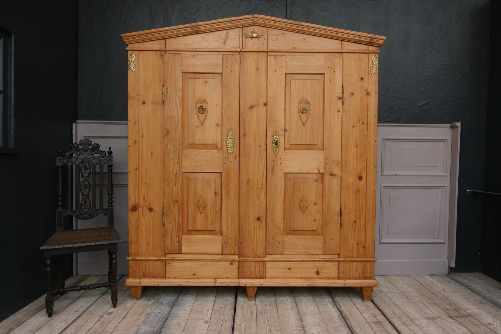 An antique classicist cabinet from the early 19th century (Biedermeier period), made of solid softwood. Waxed.
Two-door, divisible body with triangular gable standing on pointed feet.
Equipped with 3 shelves inside.